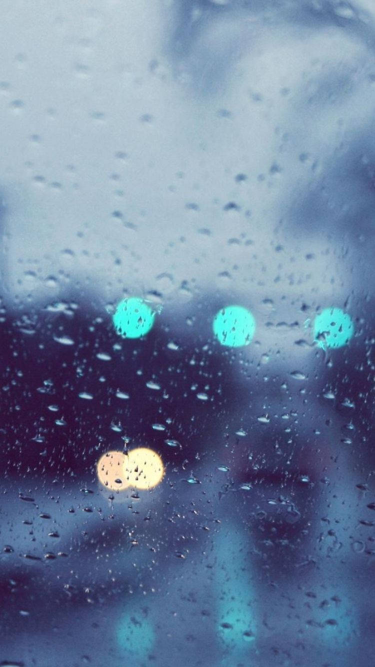 桌布 壁紙 — 雨滴模糊了窗外的景色，遠處色彩繽紛的散景燈光柔和地閃爍。