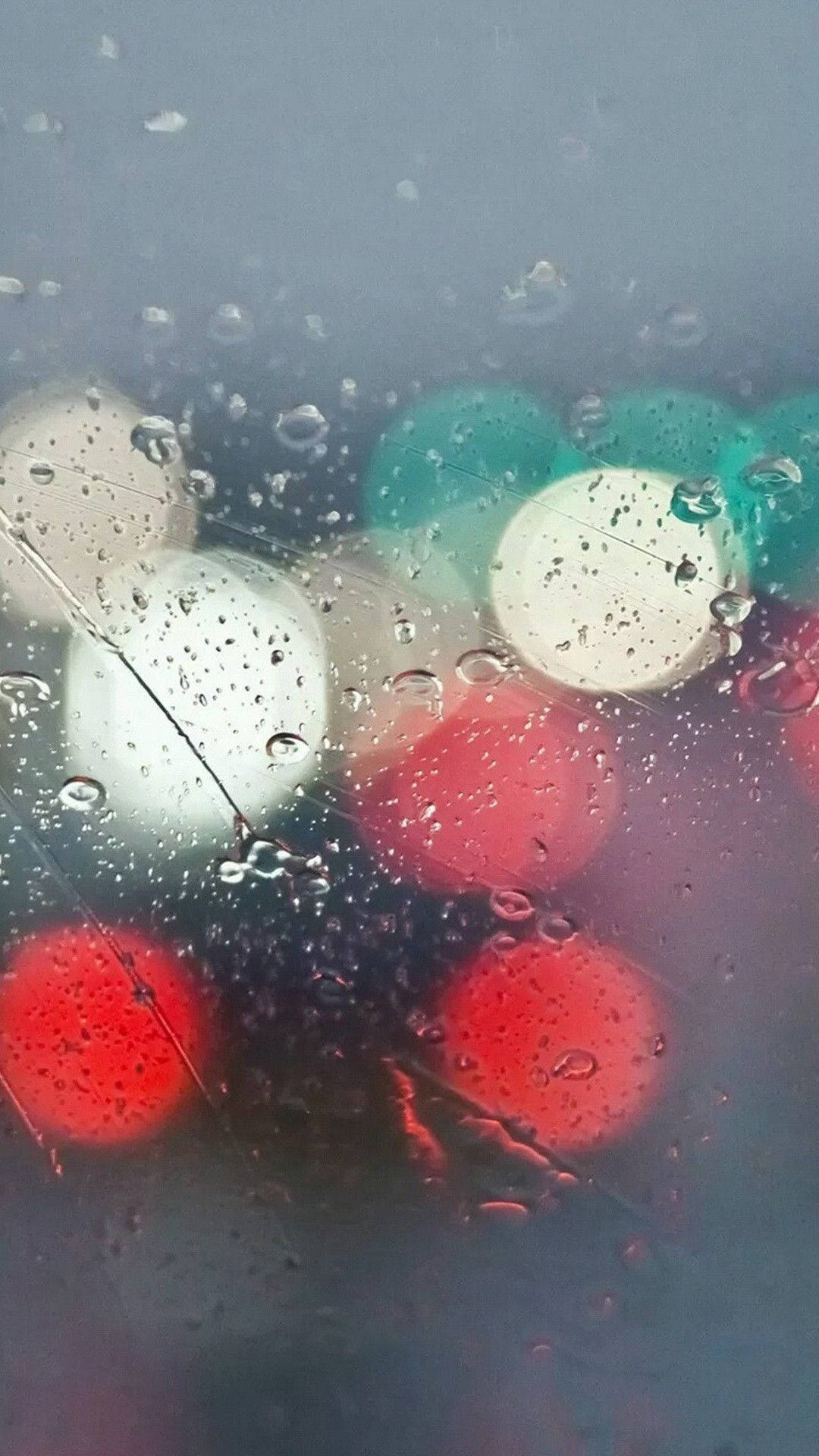 Raindrops 桌布 壁紙 — 雨滴模糊了窗玻璃上鮮豔的紅色、綠色和白色散景燈光，營造出雨夜的場景。