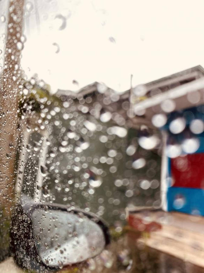 Raining 桌布 壁紙 — 雨滴模糊了透過濕窗看到的汽車側鏡和色彩繽紛的建築物。