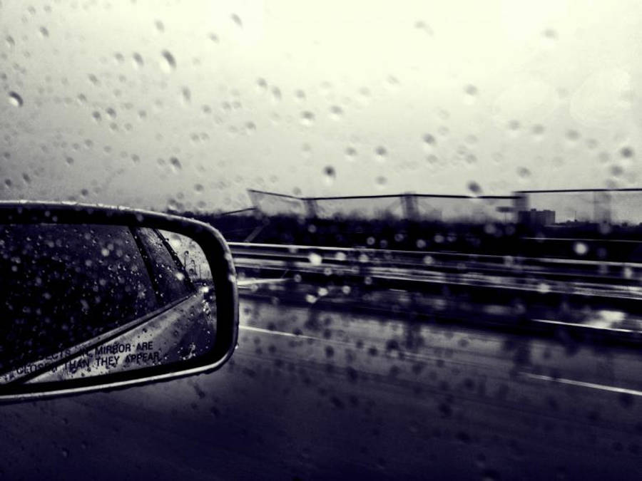 Raining 桌布 壁紙 — 雨滴模糊了透過車窗的視野，而側鏡反射出陰天潮濕的高速公路。