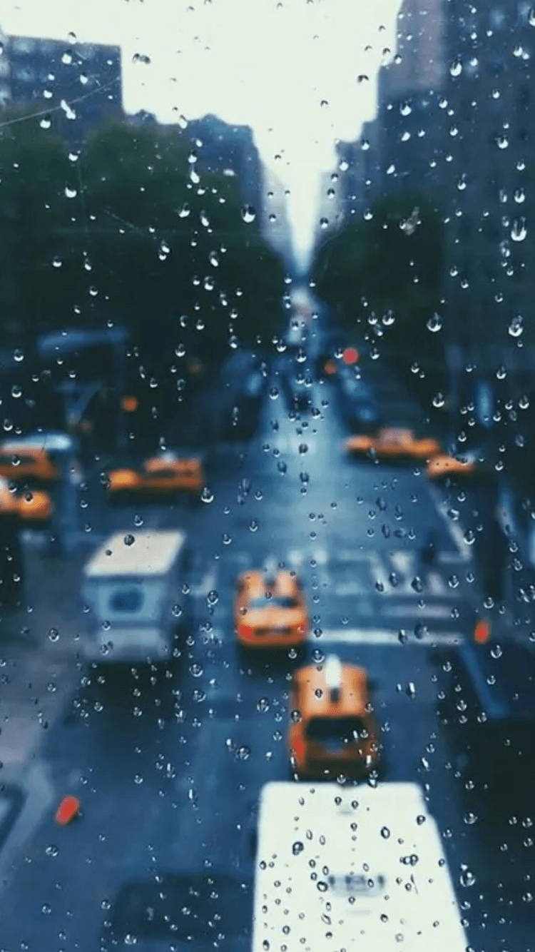 下雨 桌布 壁紙 — 雨滴模糊了陰沉日子裡透過濕窗看到的黃色計程車和城市建築的景色。
