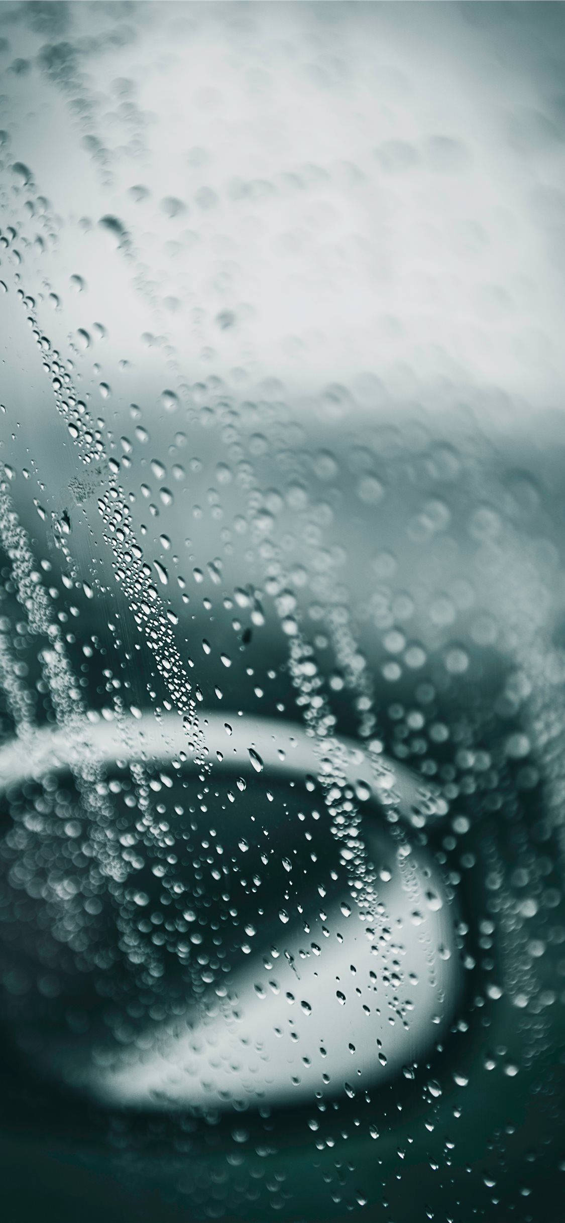 桌布 壁紙 — 雨滴沿玻璃窗流下，顯露出柔和青綠色和灰色調中的模糊圓形。