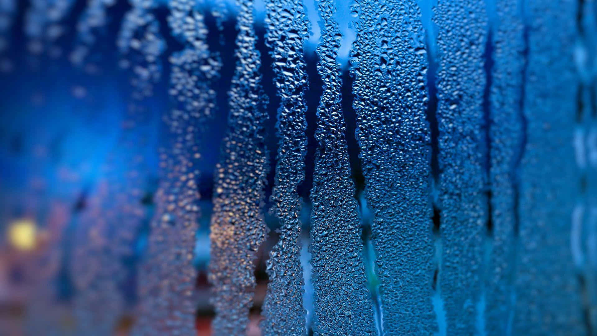Rainy Day 桌布 壁紙 — 雨滴沿玻璃窗滑落的特寫，背景是模糊的藍色和溫暖燈光。