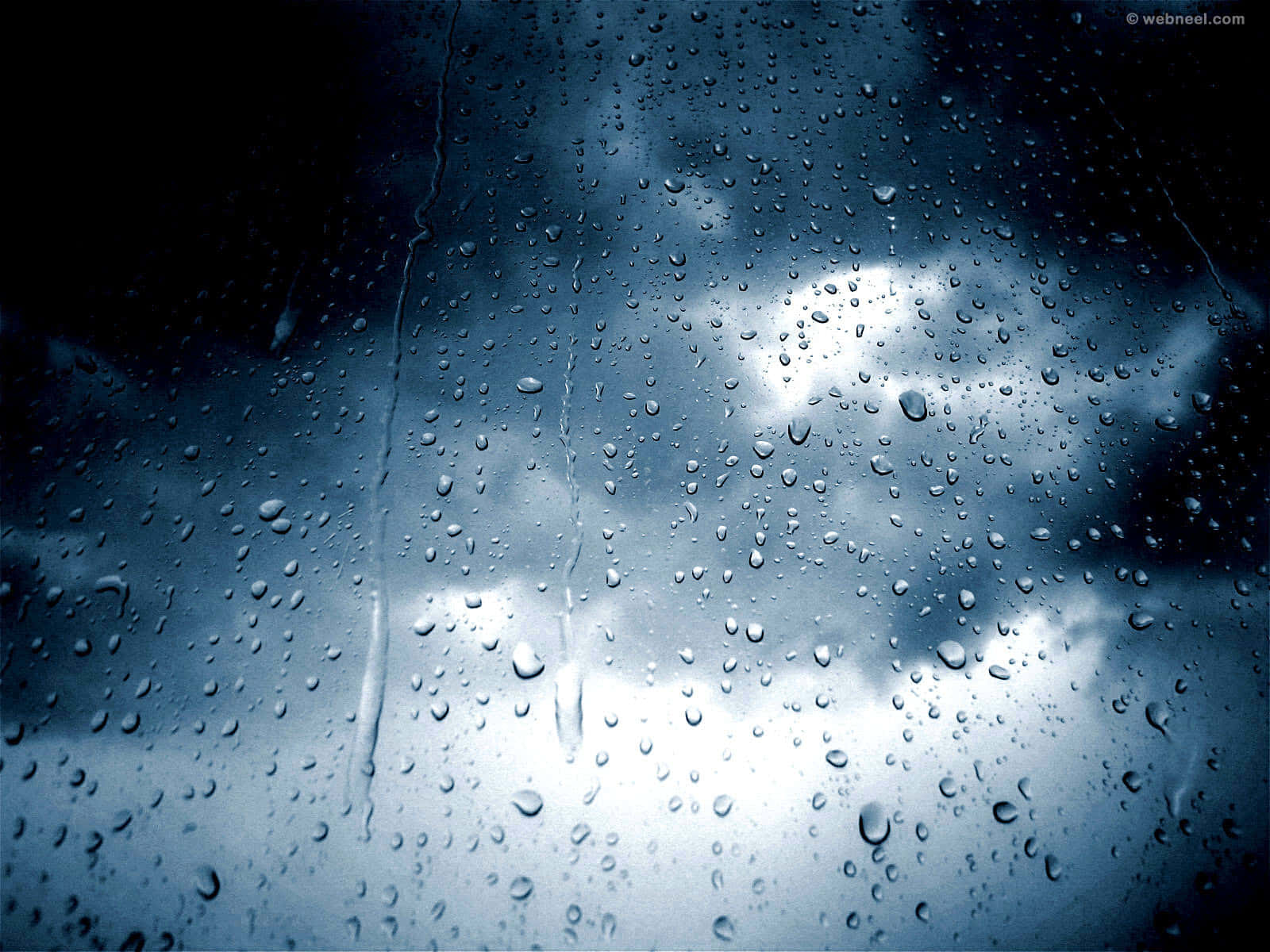 Rain Desktop 桌布 壁紙 — 雨滴沿窗戶流下，露出背後陰鬱的藍灰色天空和明亮的雲層。