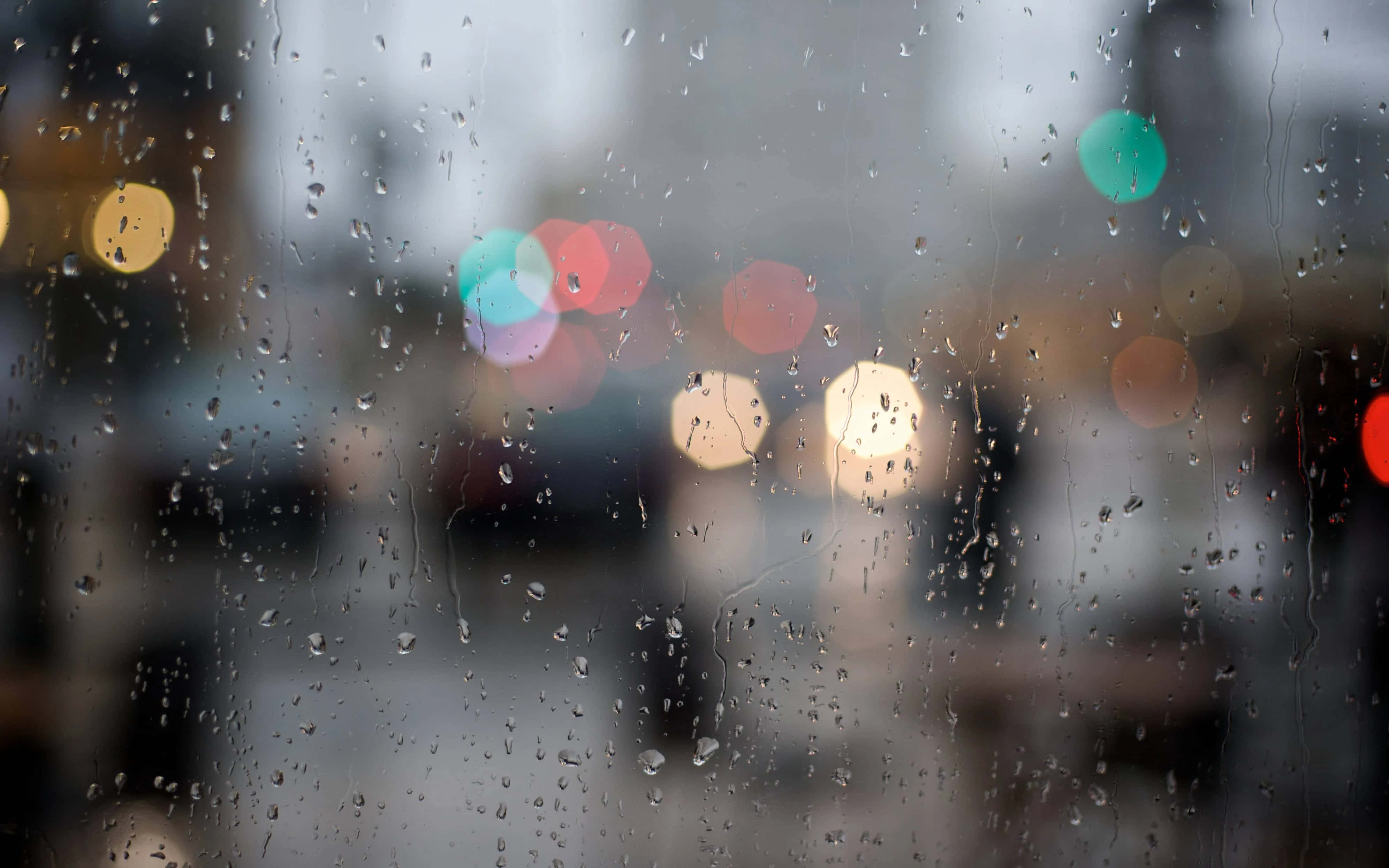 Rainy Day 桌布 壁紙 — 雨滴沿窗戶流下，顯現出模糊的城市燈光，色調冷暖交織。