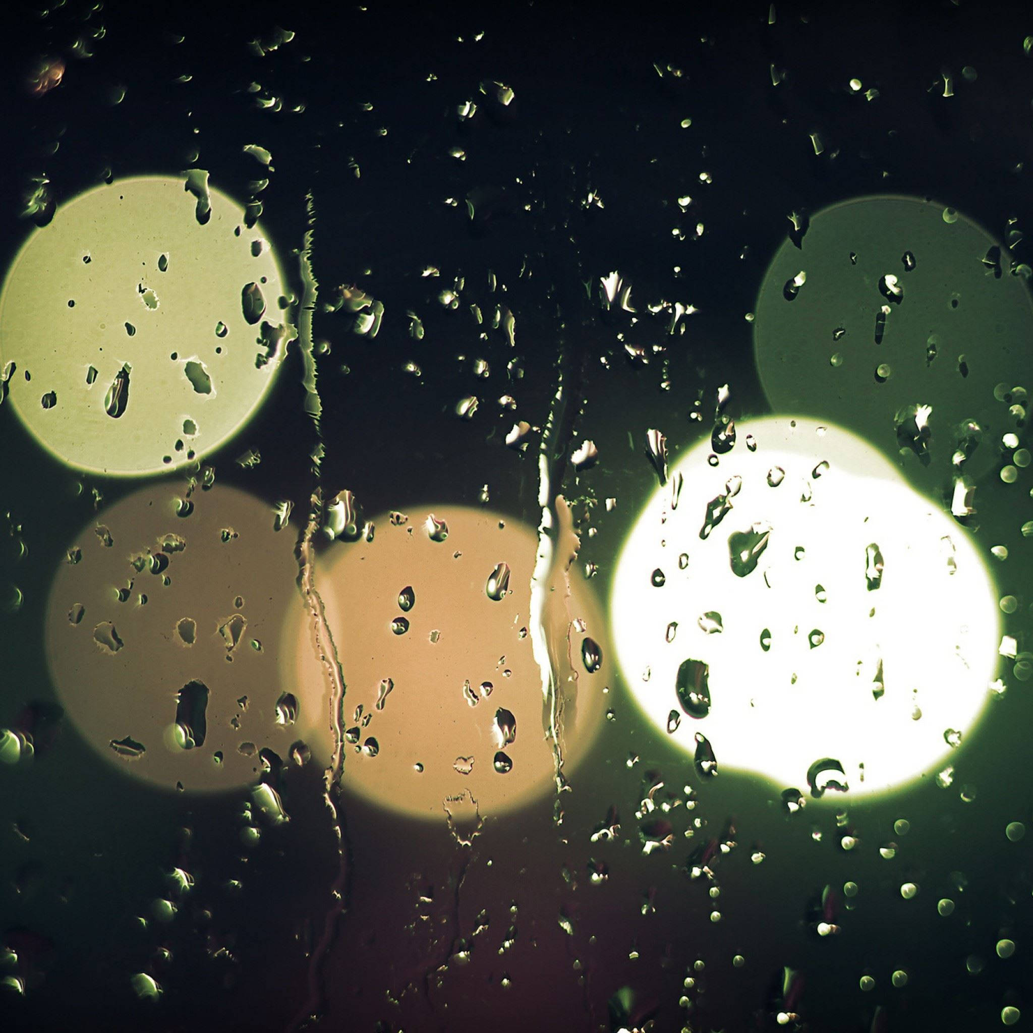 Rainy Day 桌布 壁紙 — 雨滴沿窗戶流下，顯露出黑暗夜色中模糊的溫暖燈光。