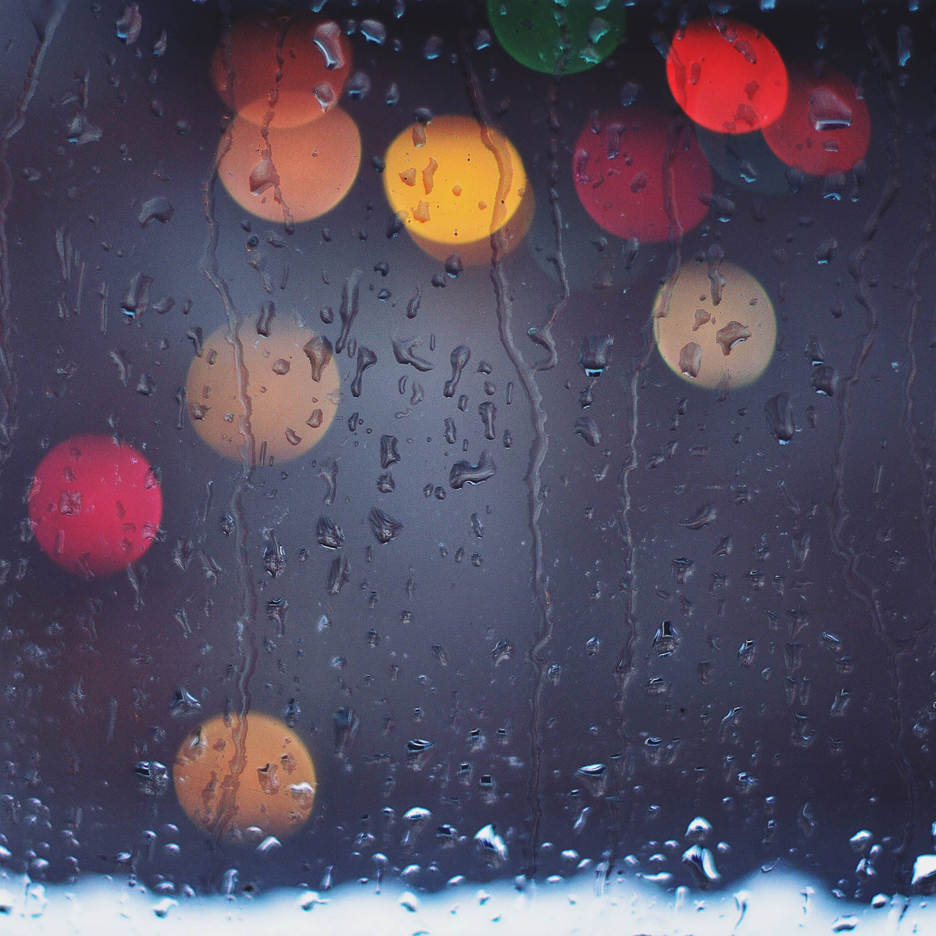 窗戶上的雨滴與夜間模糊多彩的城市燈光。 — iPad mini 動態圖片 壁紙