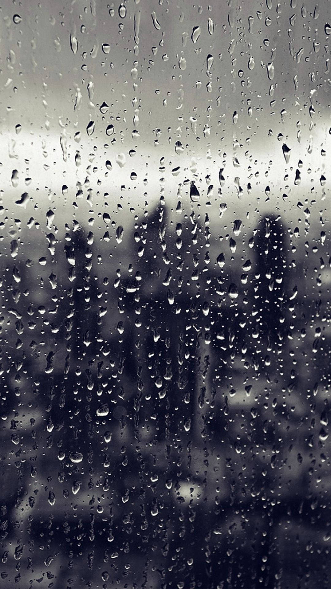 黑白 桌布 壁紙 — 雨滴沿著玻璃窗流下，模糊了灰階色調中柔和的城市景觀。