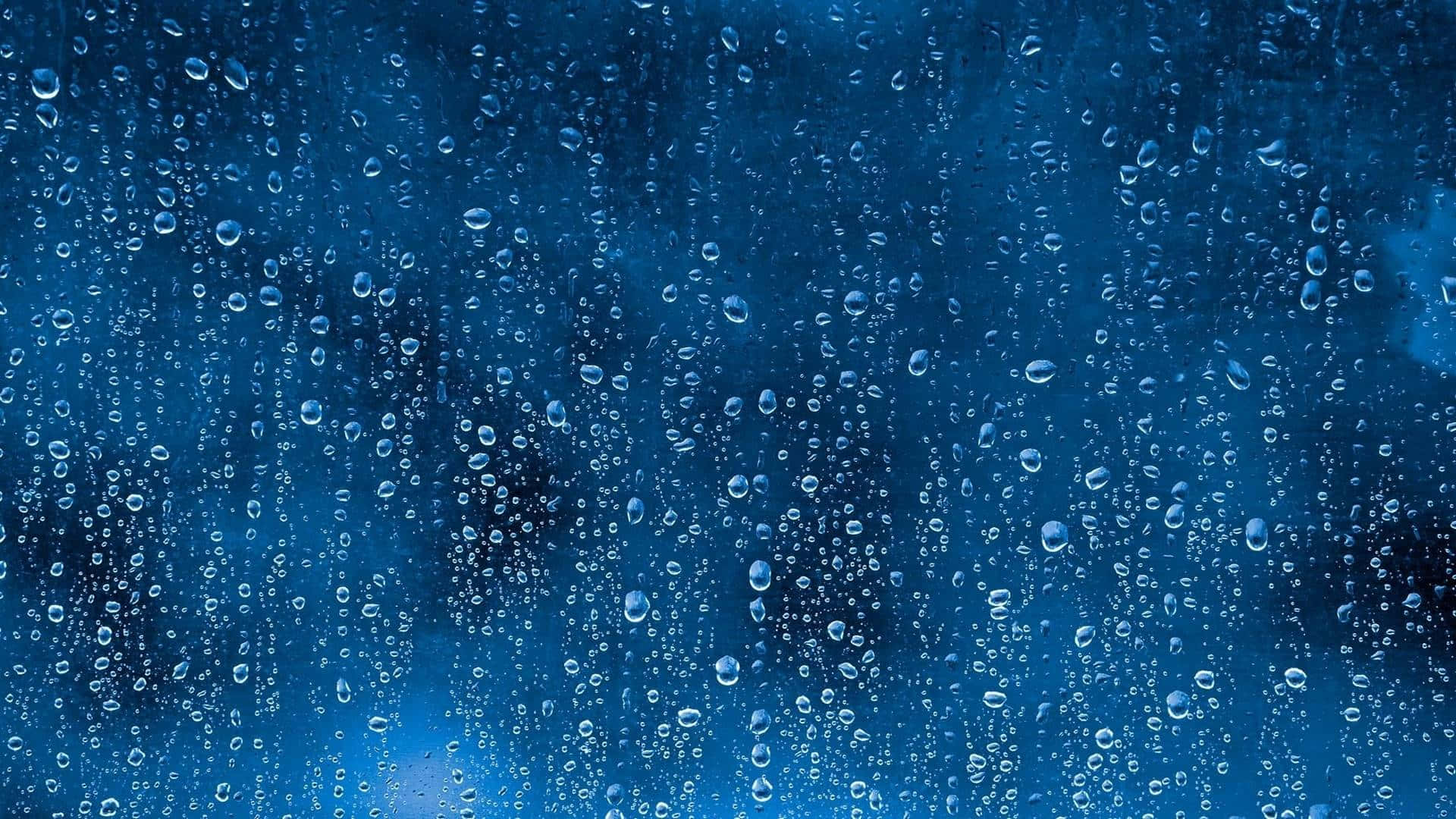 Raining 桌布 壁紙 — 雨滴沿著玻璃窗流下，背景為深藍色紋理。