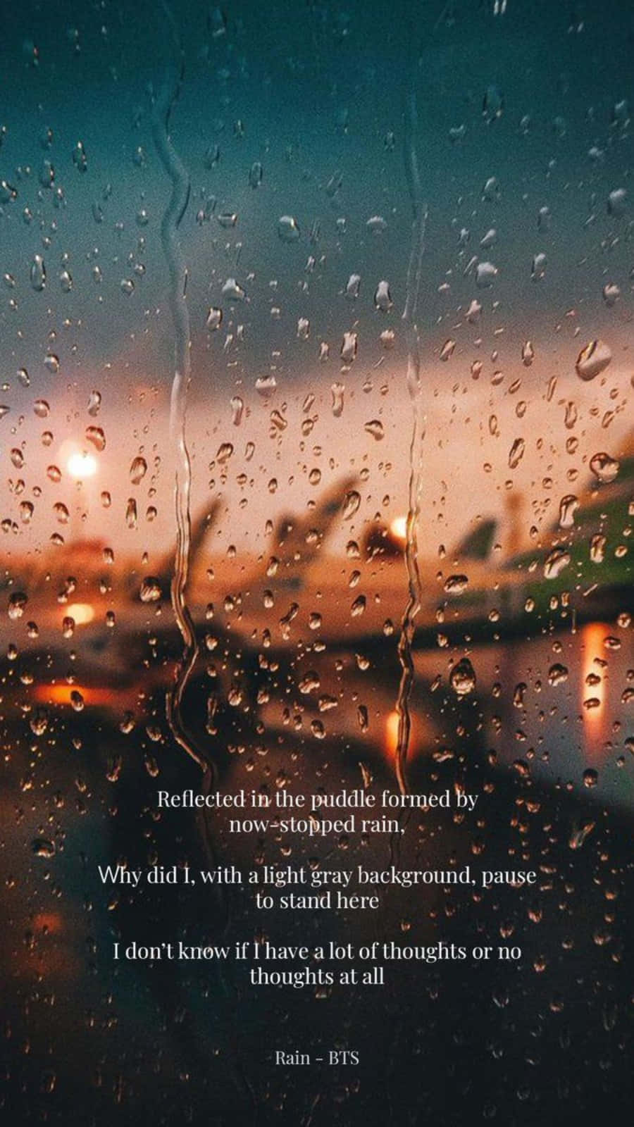 Raining 桌布 壁紙 — 雨滴沿著窗戶流下，框住了黃昏時模糊的城市景觀，溫暖的路燈透過濕玻璃閃爍。