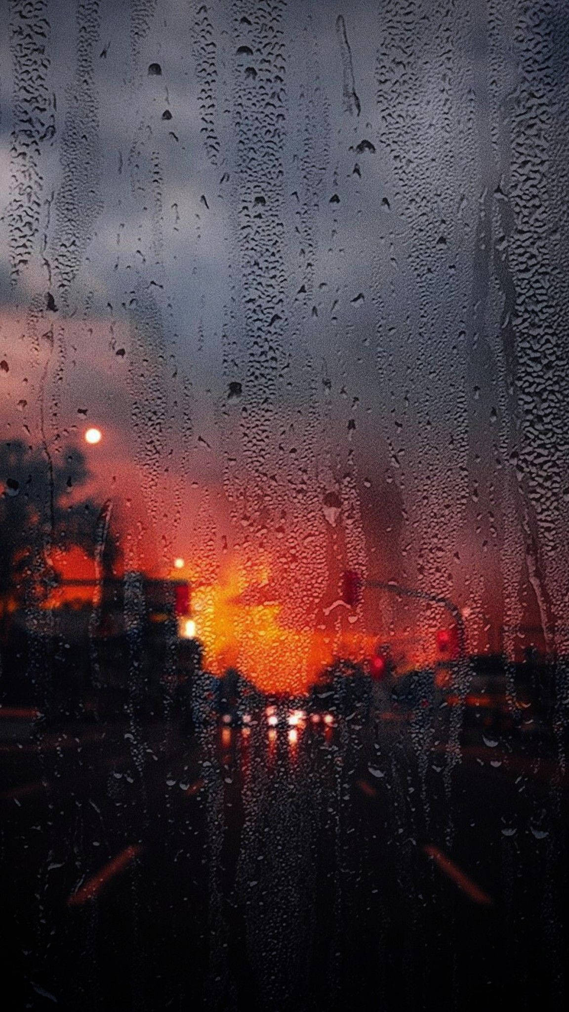 Raining 桌布 壁紙 — 雨滴沿著車窗流下，熾熱的橙色夕陽光線透過濕玻璃變得模糊。