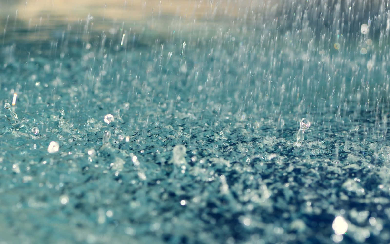 Rainy 桌布 壁紙 — 雨滴濺落，在藍綠色水面上泛起漣漪，形成閃爍的水珠和輕柔的波浪。
