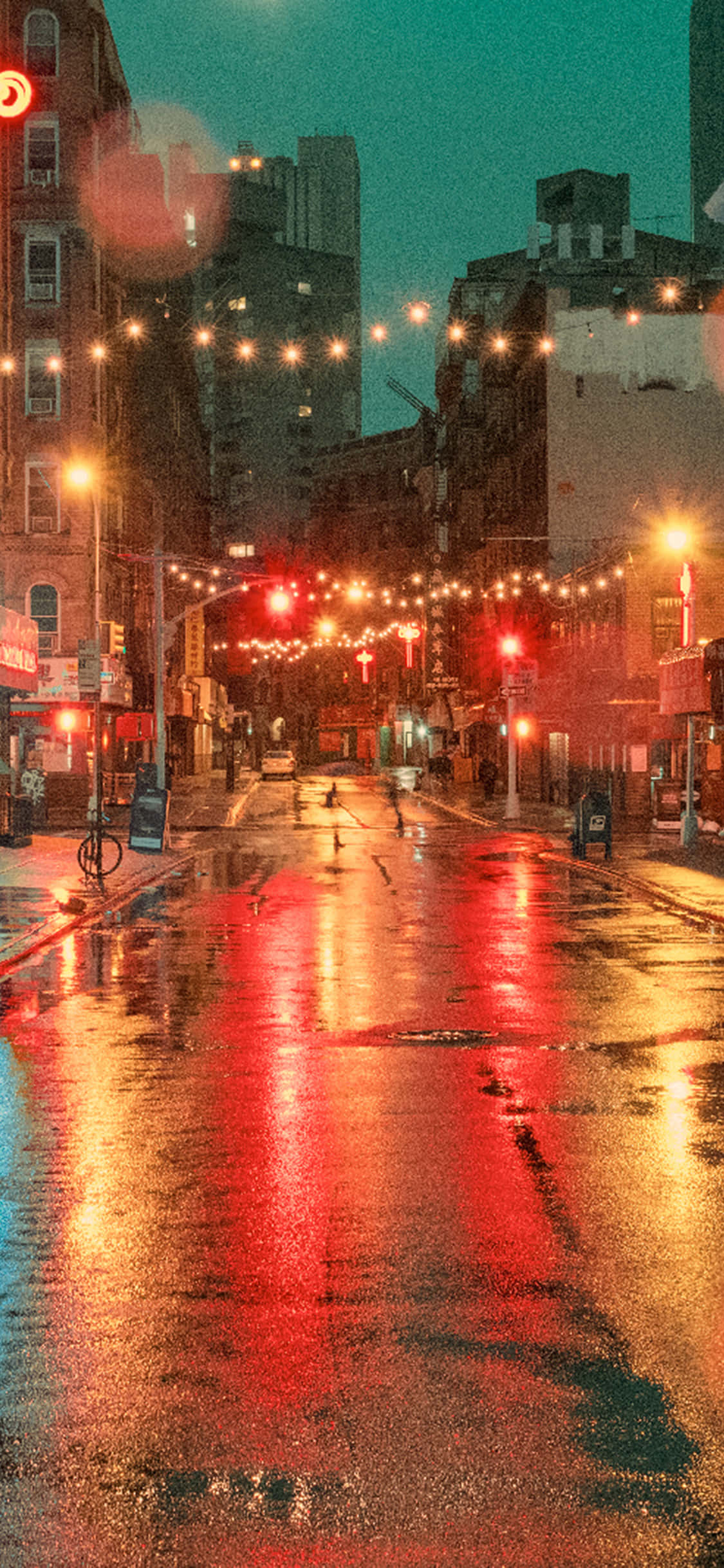 Street Light 桌布 壁紙 — 雨濕的城市街道在夜晚閃爍著紅色交通燈和溫暖的串燈，反射在濕漉漉的路面上。