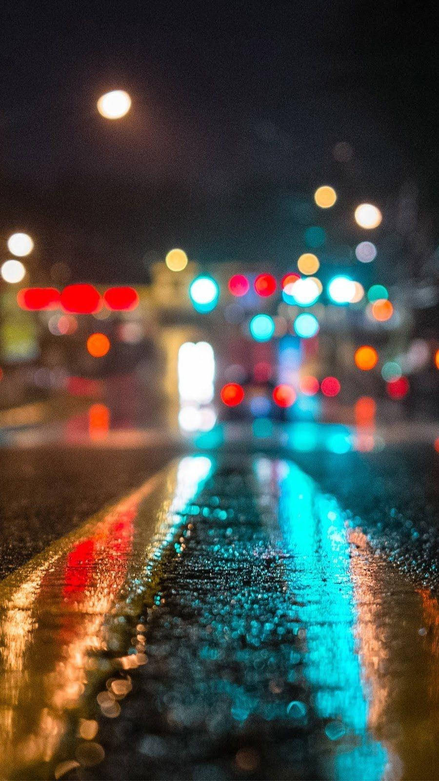Smartphone 桌布 壁紙 — 雨濕的城市街道夜晚，發光的散景燈光反射在濕瀝青上。