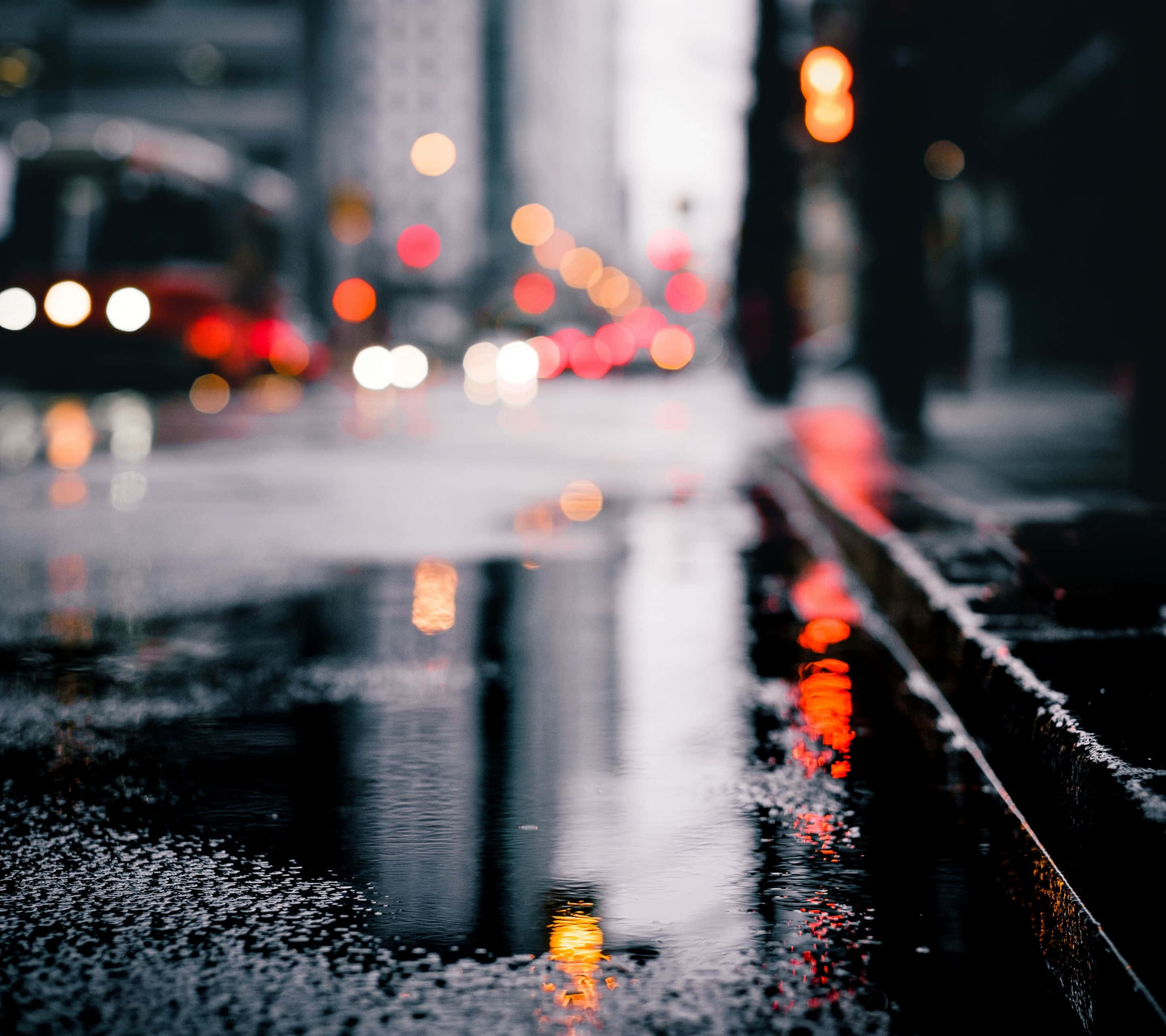 Rainy 桌布 壁紙 — 雨濕的夜晚城市街道，模糊的車燈反射在水坑和濕漉漉的路面上。