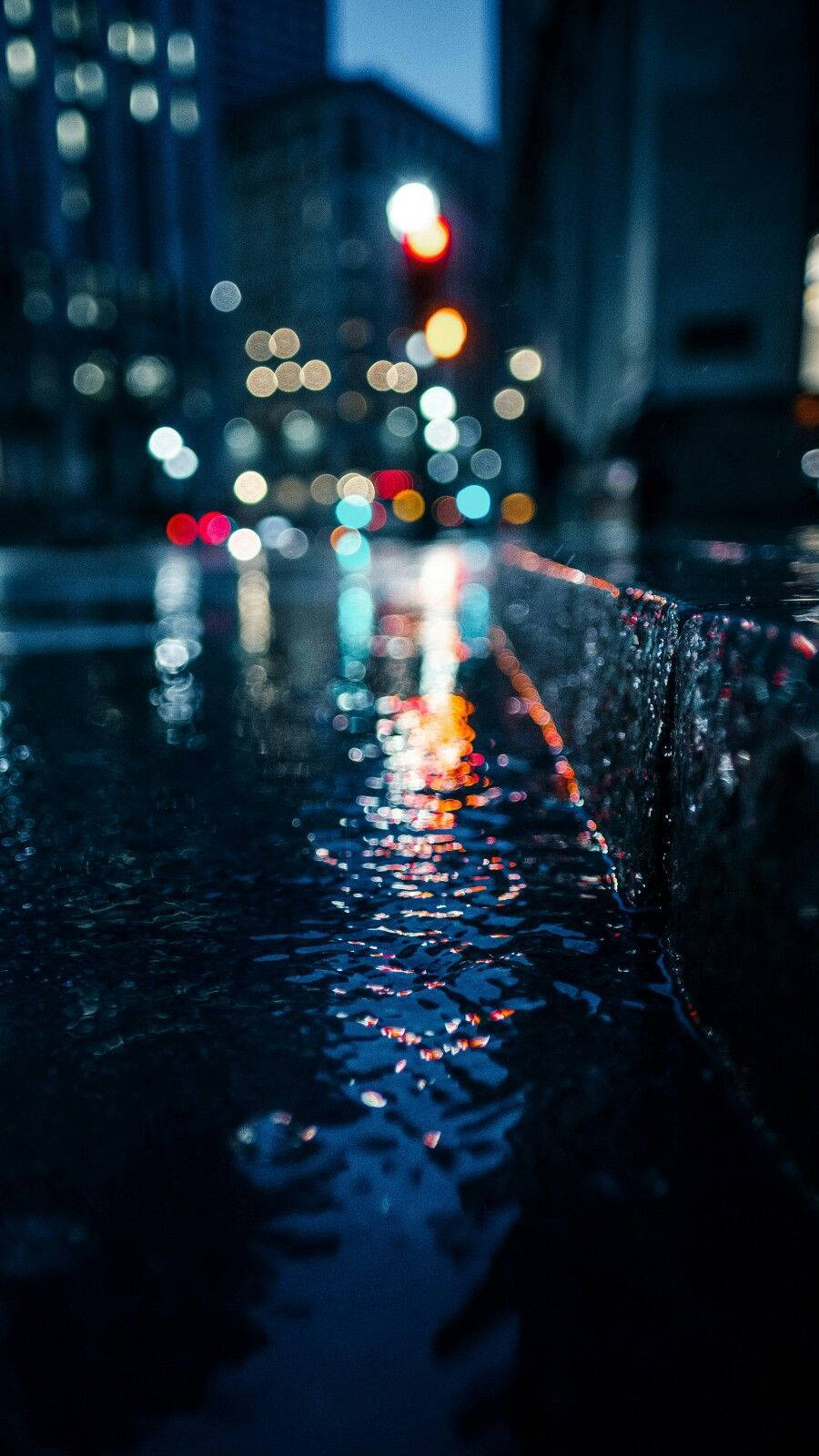 Rain 4K 桌布 壁紙 — 雨濕的夜晚城市街道，水坑和濕漉漉的路面上反射著發光的散景燈光。
