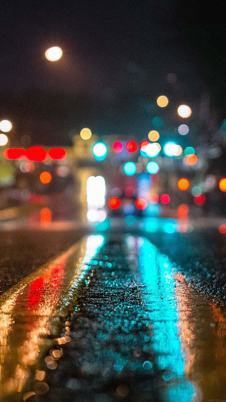 桌布 壁紙 — 雨濕的夜晚城市街道，濕漉漉的瀝青上反射著發光的散景燈光。