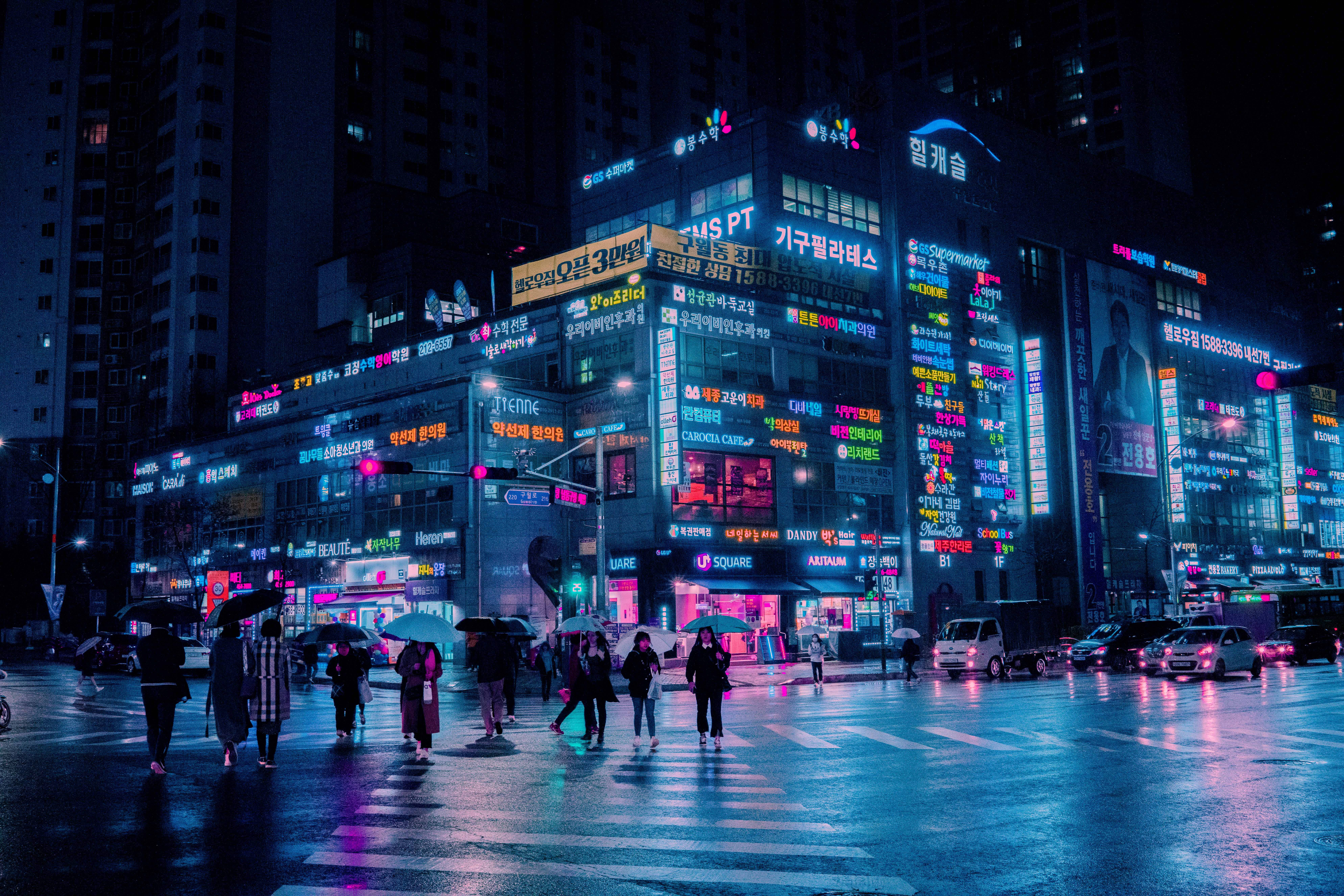 Dark Neon 桌布 壁紙 — 雨濕的夜晚城市街道，霓虹招牌閃爍，行人撐傘過馬路。