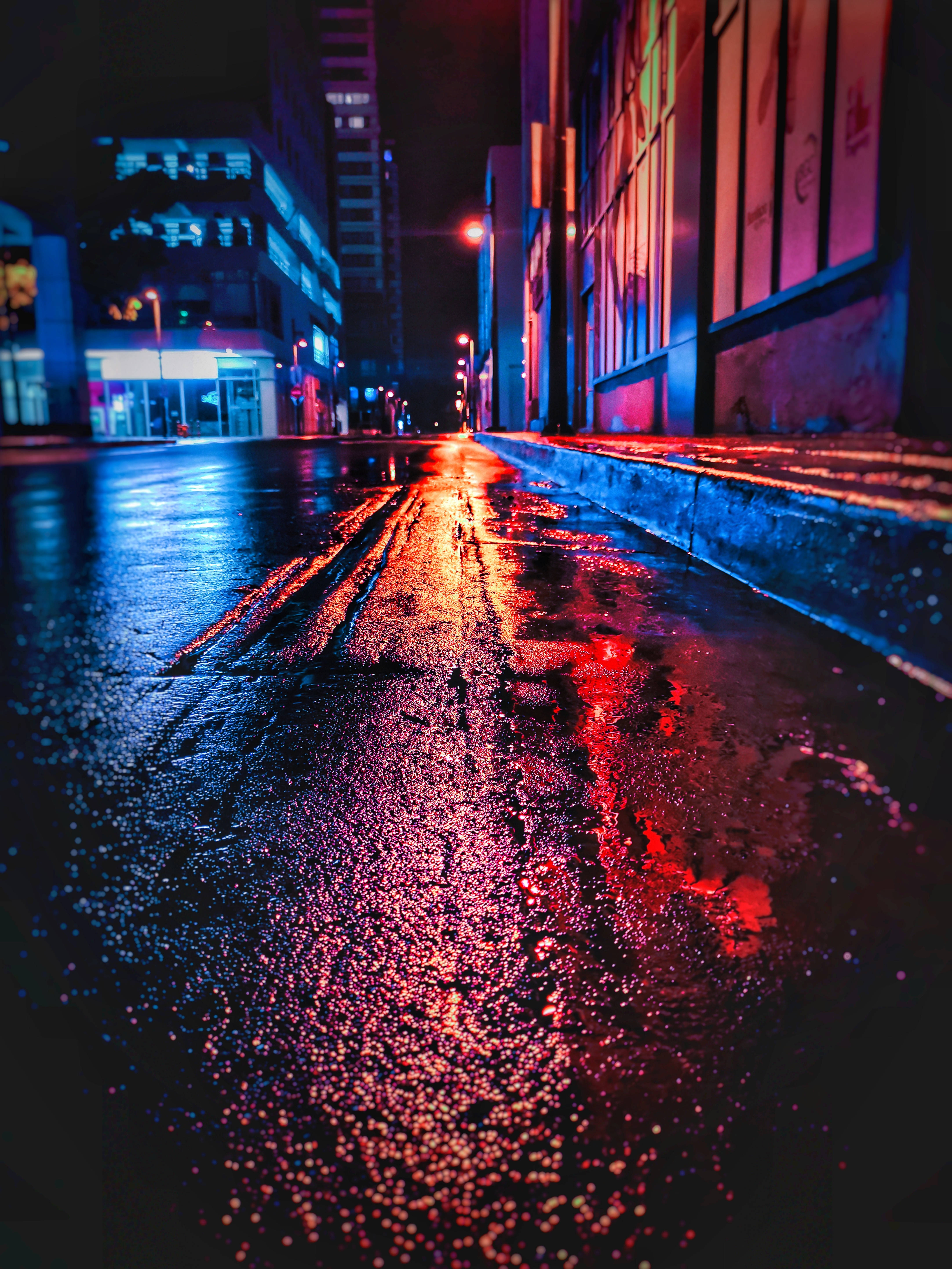 霓虹城市動態圖 桌布 壁紙 — 雨濕的夜晚城市街道反射出鮮豔的紅色和藍色霓虹燈光。