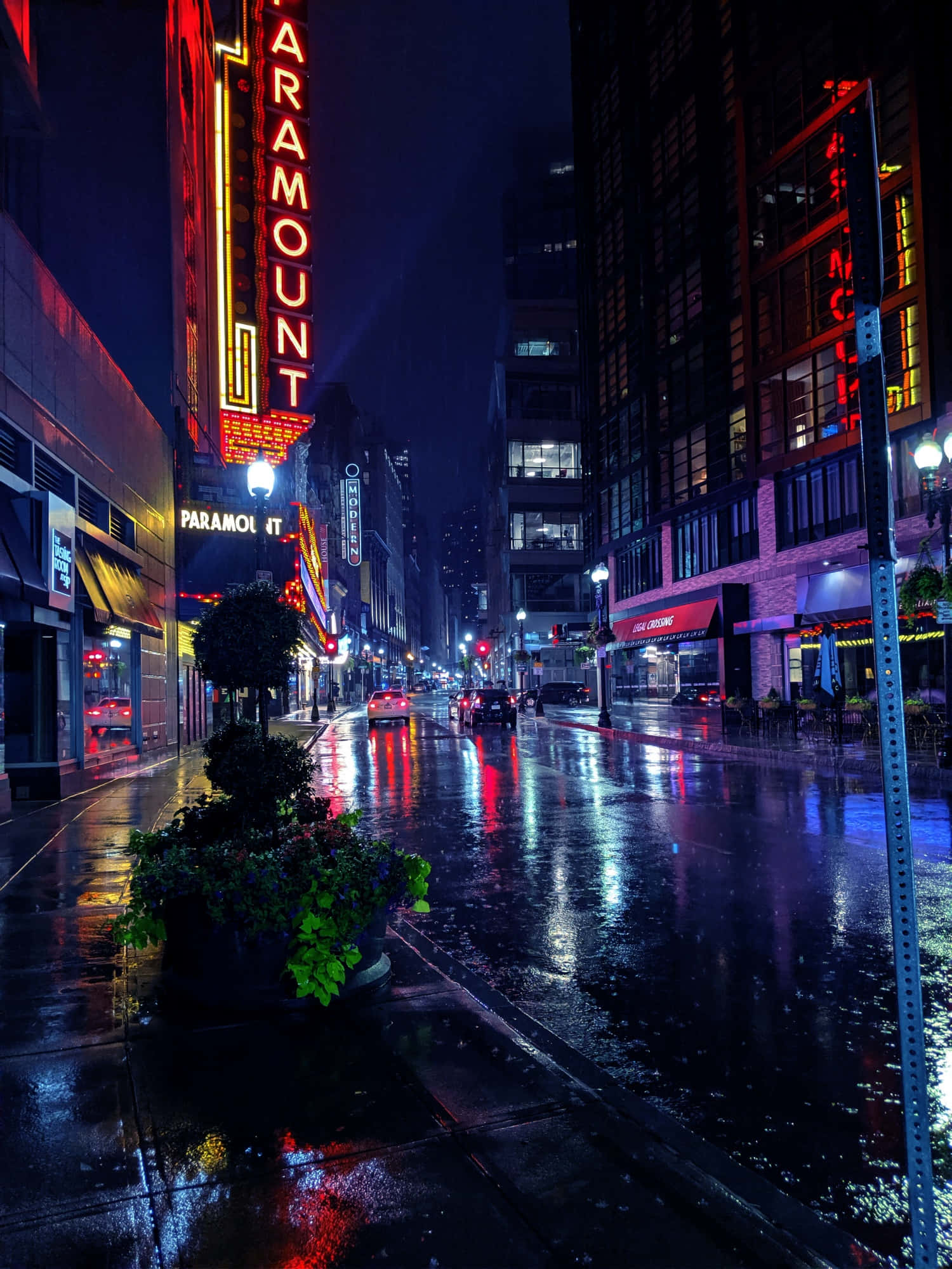 Vibey 桌布 壁紙 — 雨濕的夜晚城市街道反射著高聳建築物的霓虹燈光，包括一個發光的Paramount標誌。