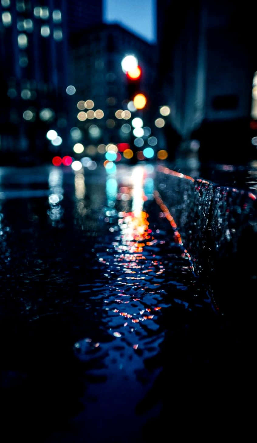lights 桌布 壁紙 — 雨濕的夜晚城市街道在黑暗天空下閃爍的水坑中反射出模糊的霓虹燈光。