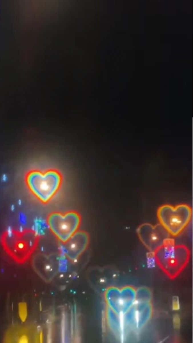 心形美學 桌布 壁紙 — 雨濕的夜晚街道閃爍著彩色心形燈光，倒映在濕漉漉的路面上。