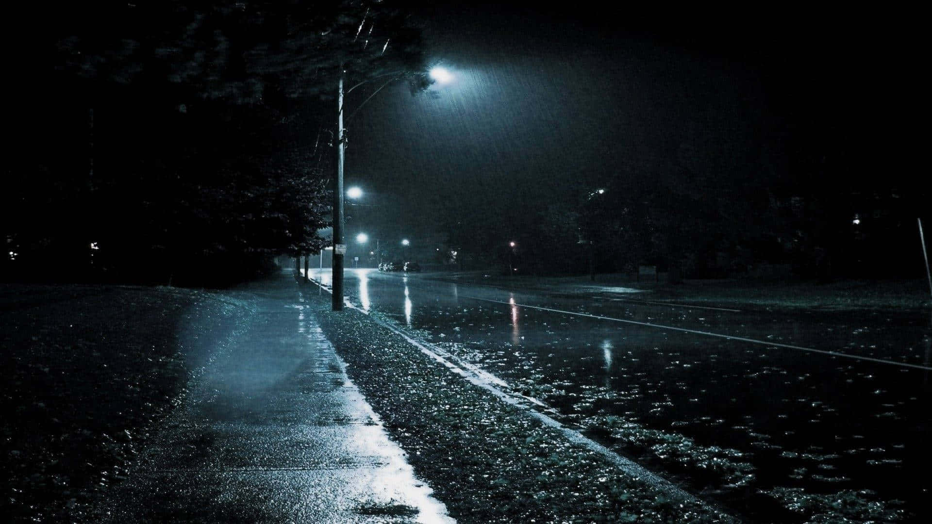Rain Desktop 桌布 壁紙 — 雨濕的夜間城市街道，被刺眼的街燈照亮，透過落下的雨水投下長長的影子。