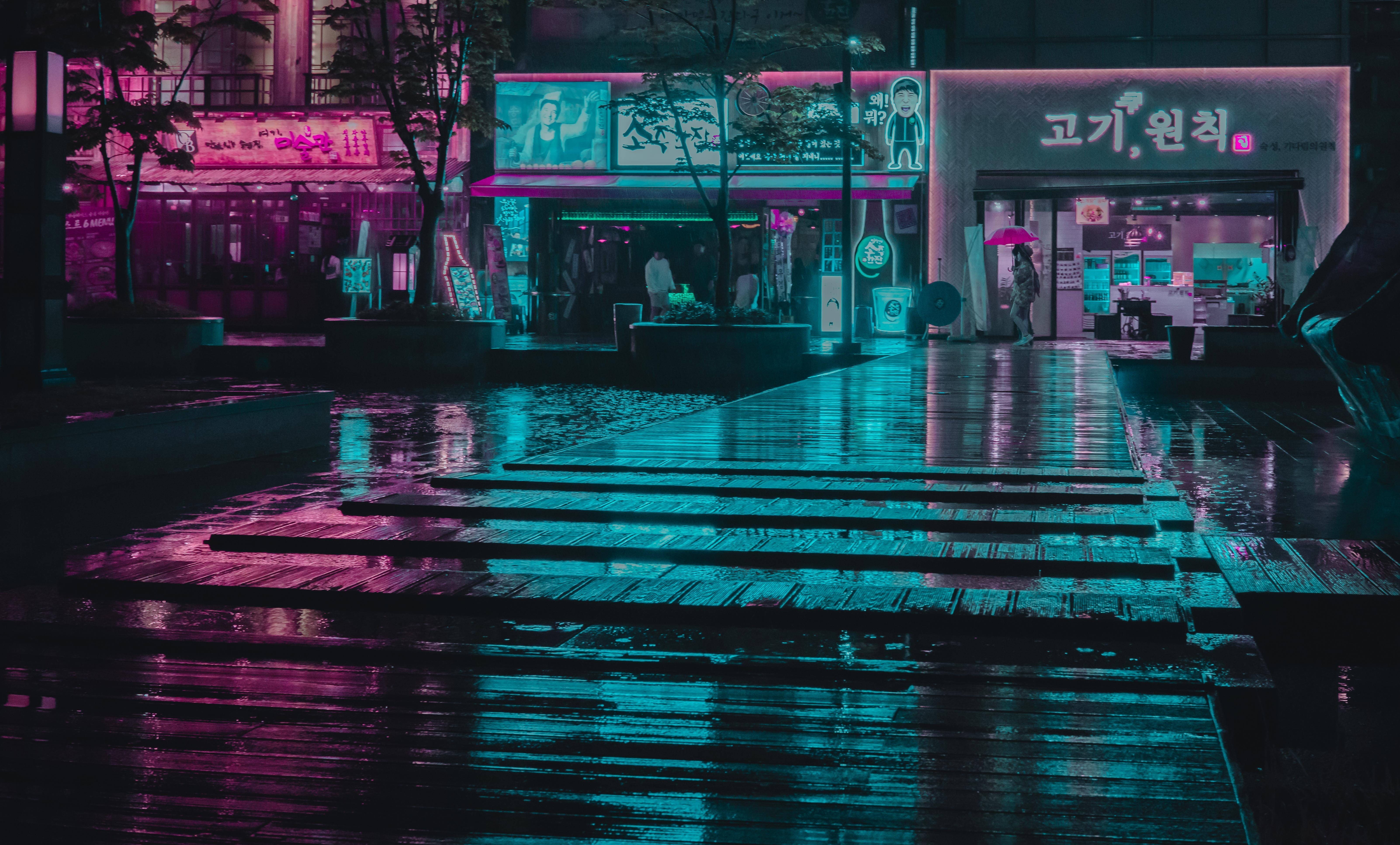 Vaporwave 桌布 壁紙 — 雨濕的夜間城市街道反射著發光店面和招牌的霓虹粉紅與青色燈光。