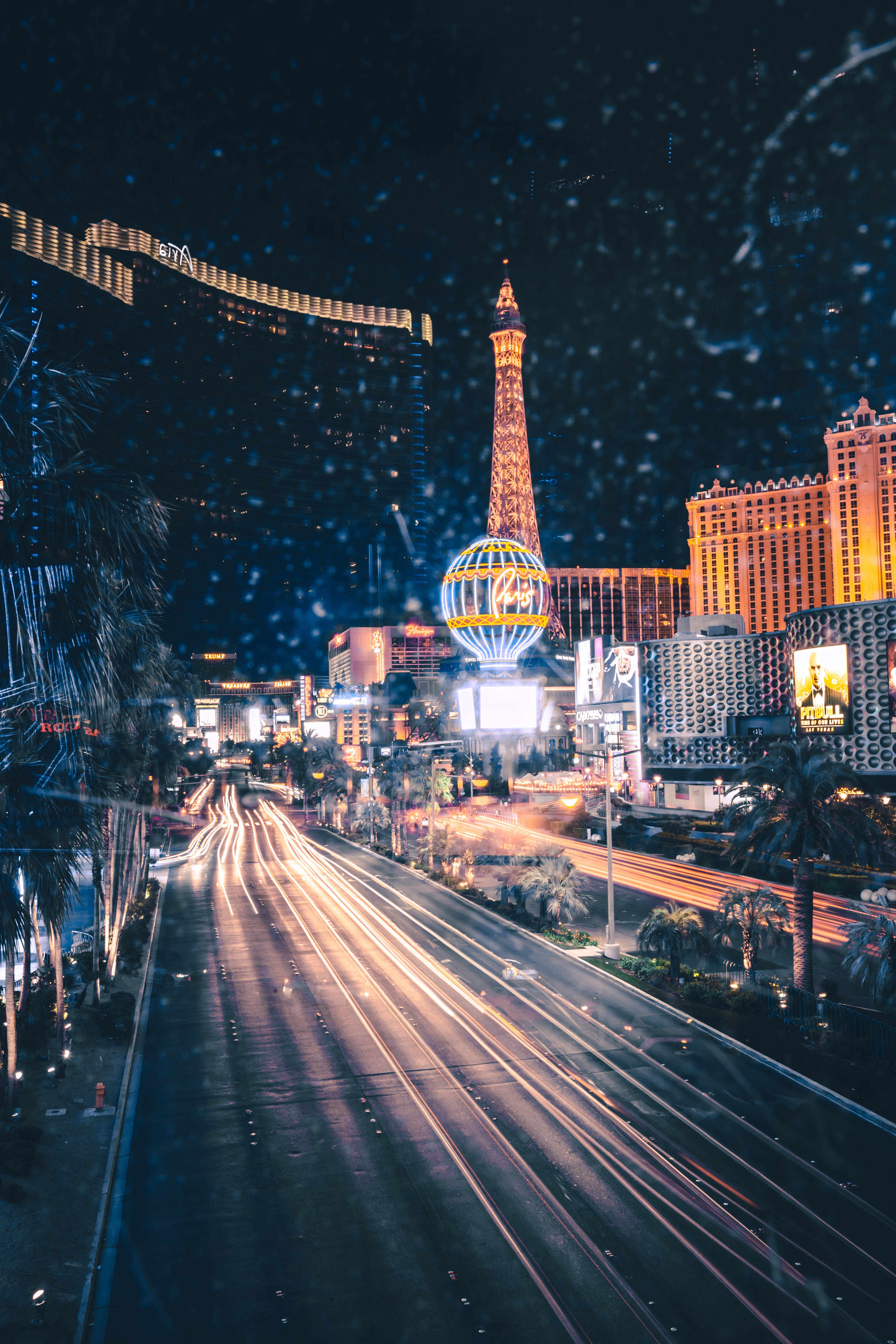 Las Vegas 4K 桌布 壁紙 — 雨濕的拉斯維加斯夜晚街道，黑暗天空下汽車的光跡和發光的酒店招牌。
