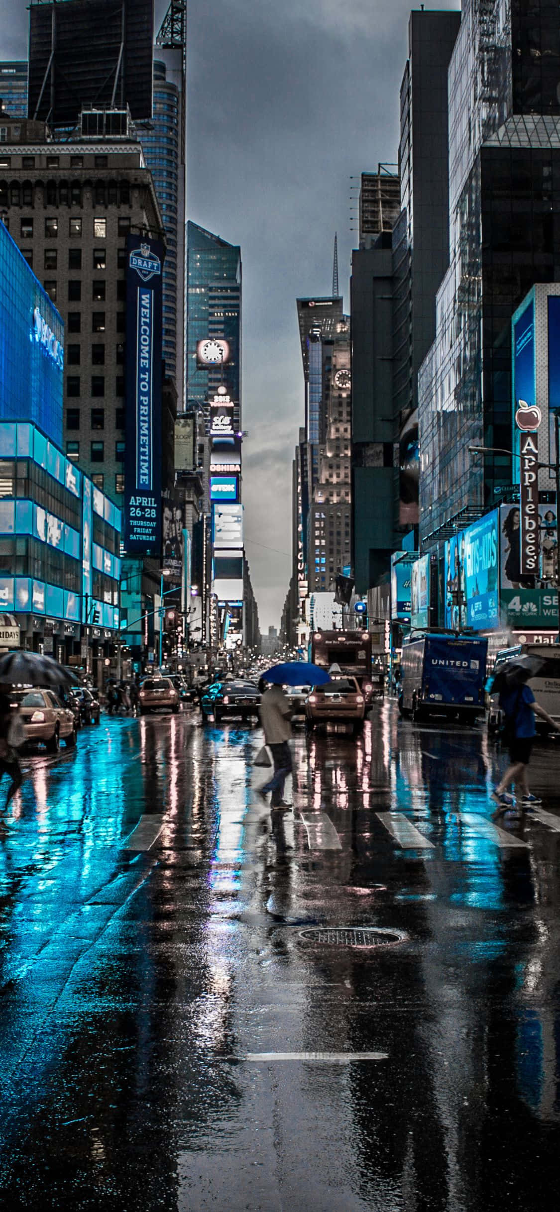 iPhone X New York 桌布 壁紙 — 雨濕的時代廣場夜晚，在高聳的摩天大樓下，濕漉漉的人行道上閃爍著霓虹燈的倒影。