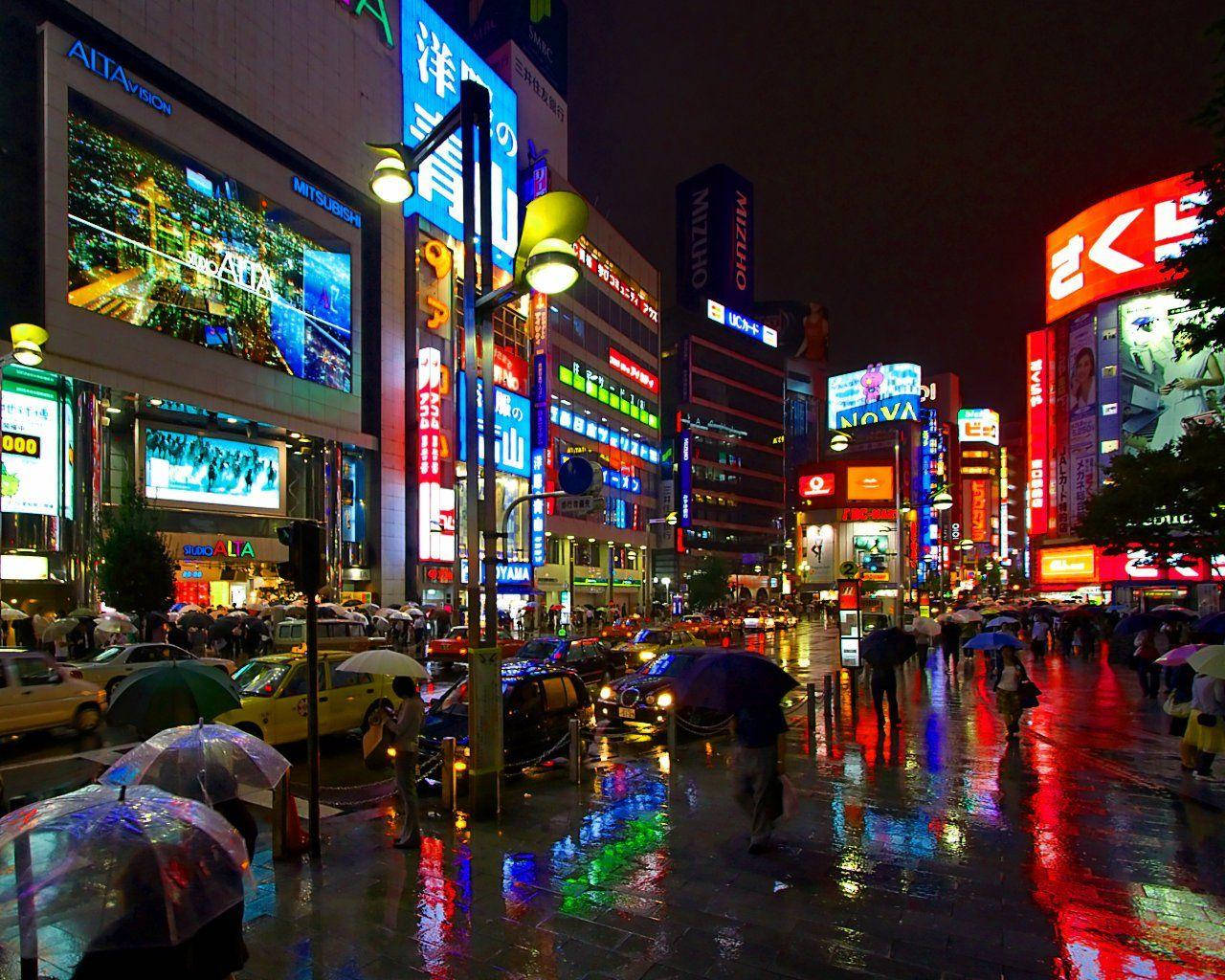 X 桌布 壁紙 — 雨濕的東京夜晚街道，霓虹招牌在濕漉漉的人行道上閃爍，行人撐著傘。