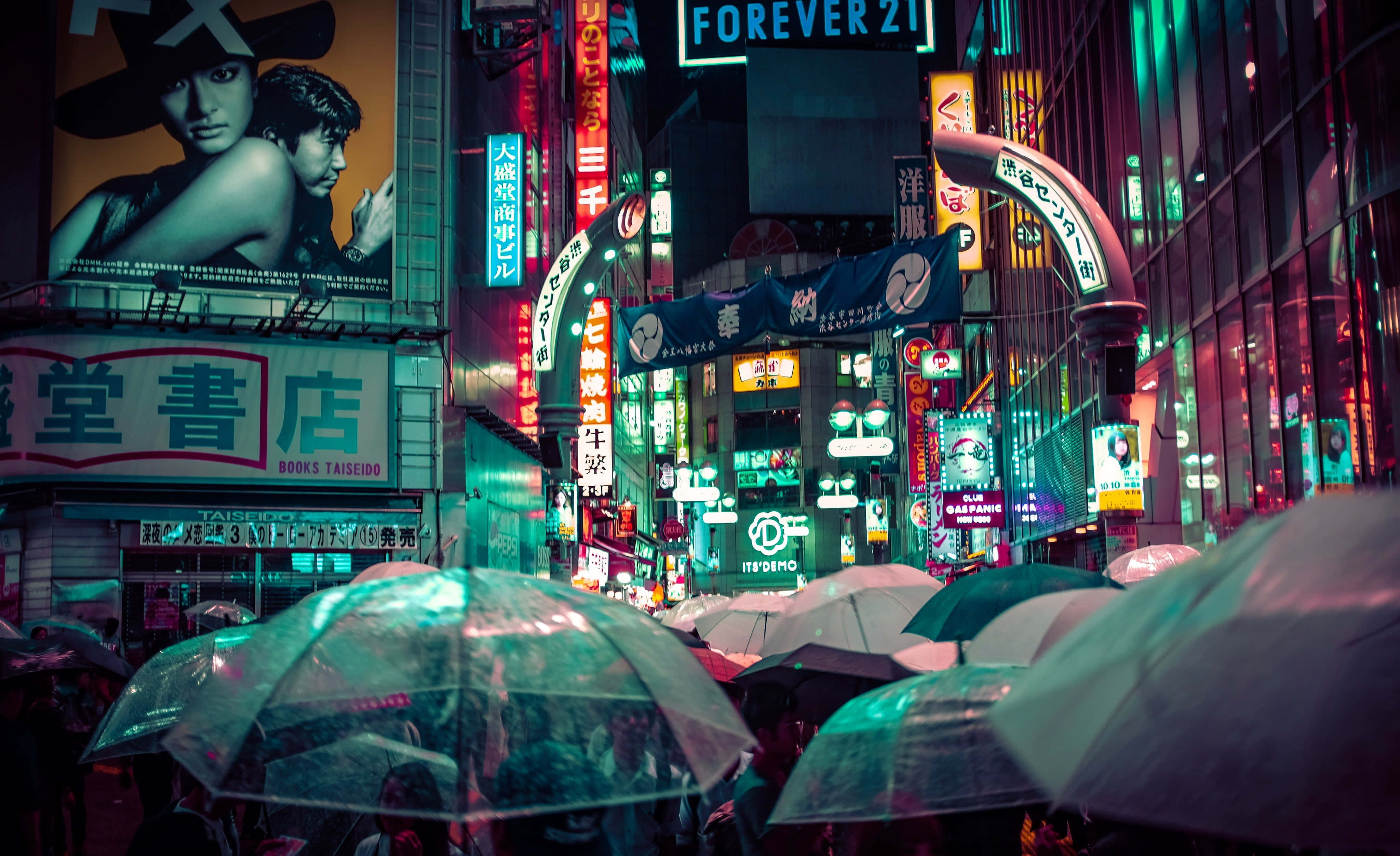 永遠21 桌布 壁紙 — 雨濕的東京夜晚街道，霓虹招牌閃爍，擠滿了撐傘的人們。