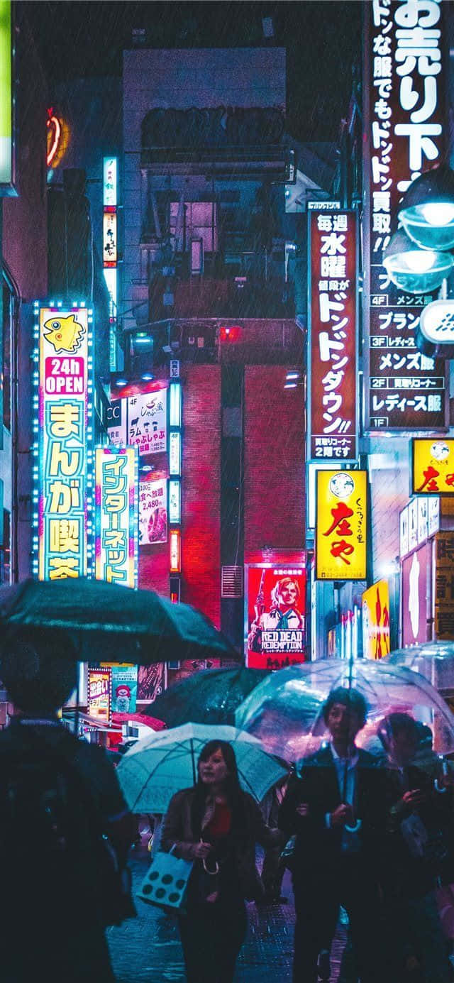 Japanese Phone 桌布 壁紙 — 雨濕的東京街道夜晚，霓虹燈閃爍，人們在街燈下撐傘。