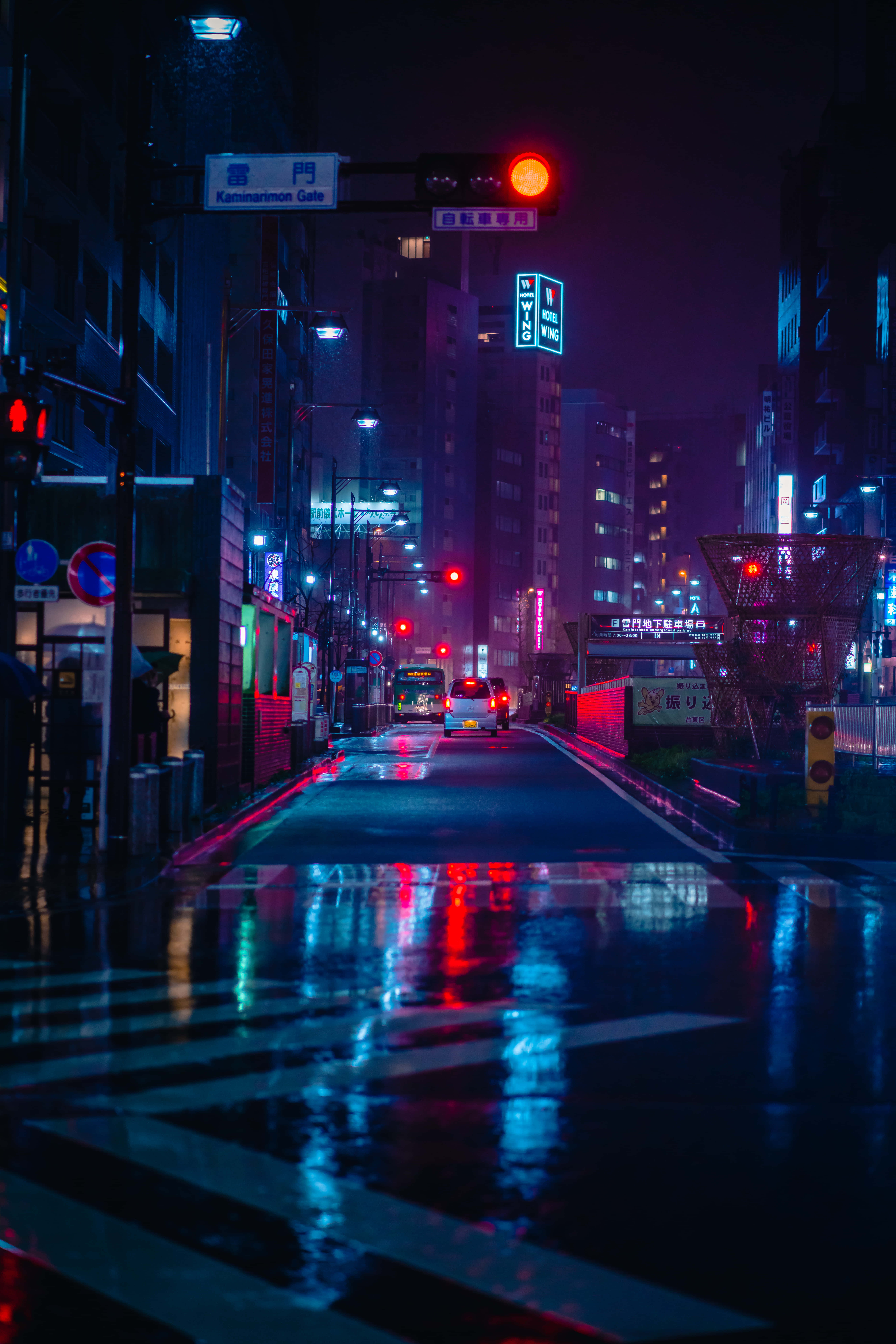 桌布 壁紙 — 雨濕的東京霓虹燈街道在夜晚反射出交通號誌和招牌的鮮豔紅藍燈光。