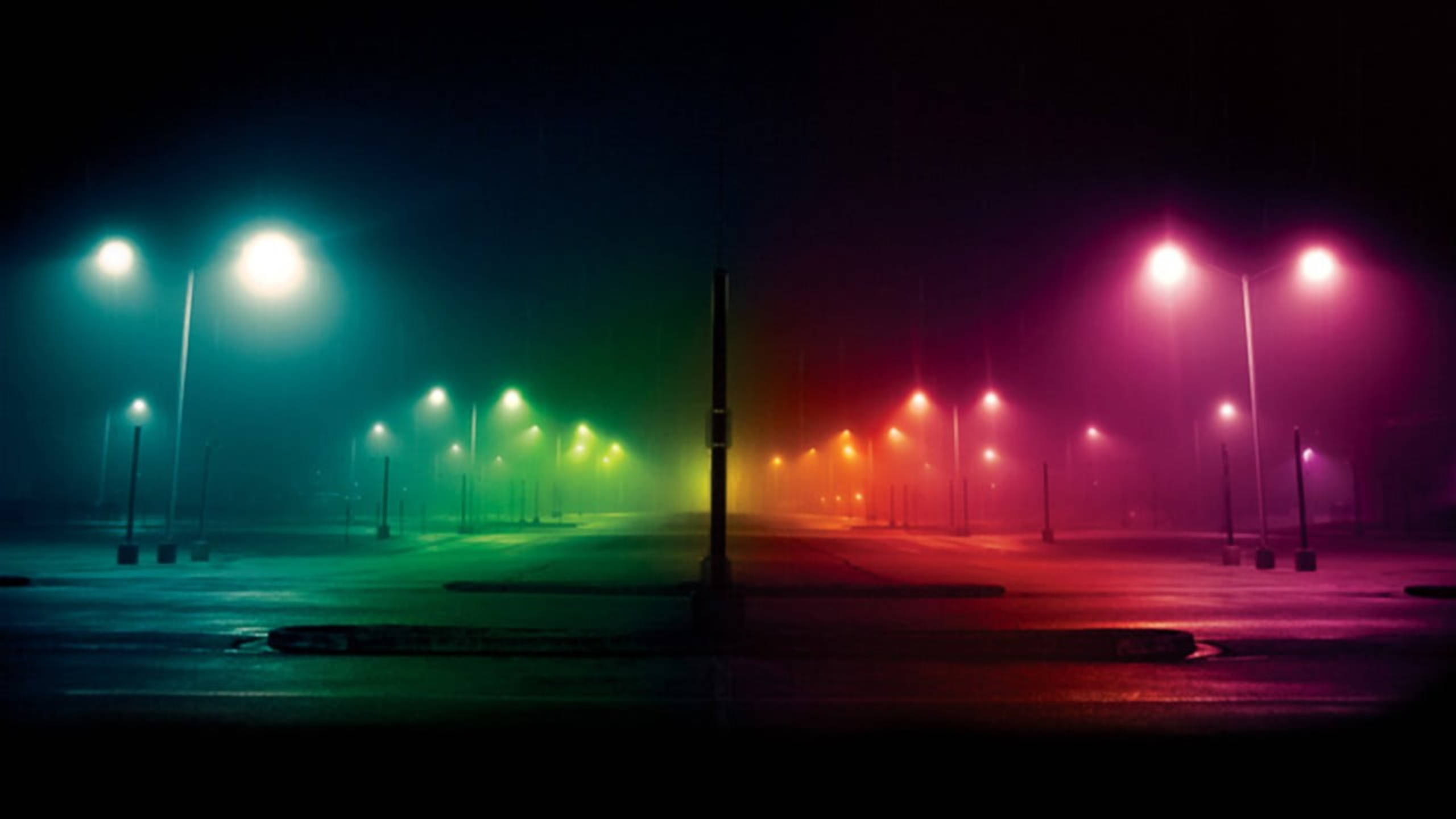 Spectrum 桌布 壁紙 — 雨濕的空蕩街道在夜晚沐浴在街燈的超現實漸變燈光中，透過薄霧投射出鮮豔的青綠色到洋紅色的光芒。