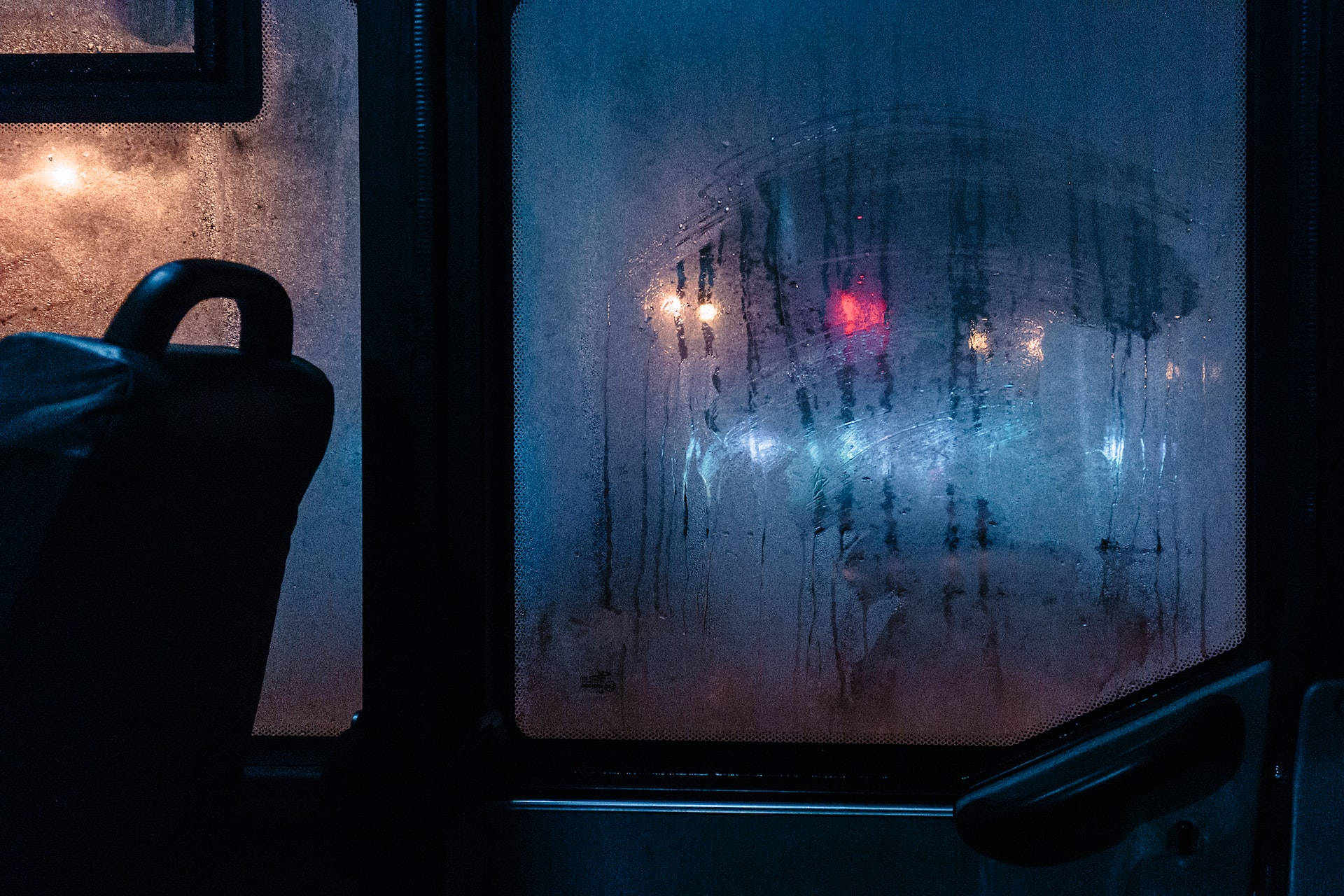 Bus 桌布 壁紙 — 雨痕模糊了巴士車窗外的景色，夜間潮濕的玻璃上反射著閃爍的城市燈光。