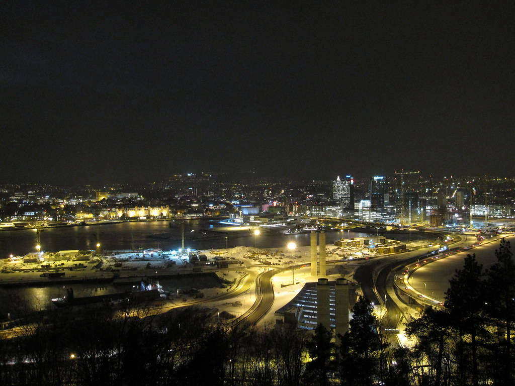 夜空 桌布 壁紙 — 雪夜城市景觀，發光的街燈和建築物倒映在冰冷的水面上。