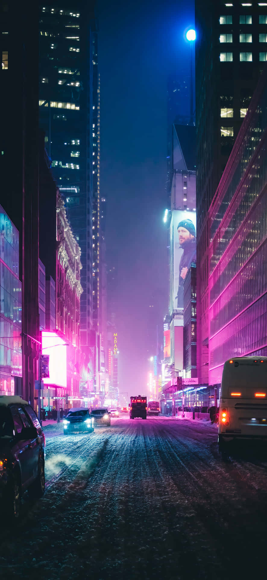 Dark Downtown Street At Night 壁紙 — 雪夜的城市街道，被高聳摩天大樓和廣告牌上鮮豔的粉紅和藍色霓虹燈照亮。