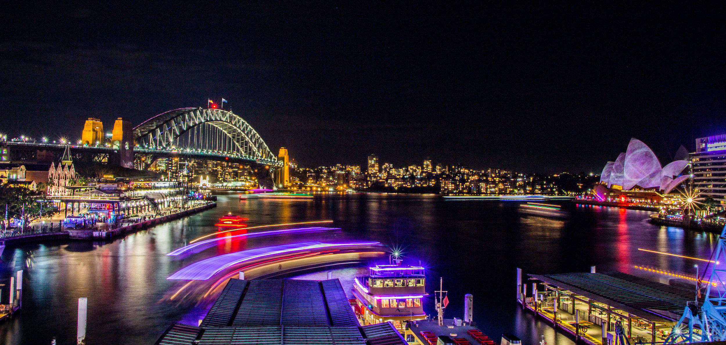 Sydney 桌布 壁紙 — 雪梨港的璀璨夜景，燈火通明的港灣大橋和歌劇院倒映在水面上。