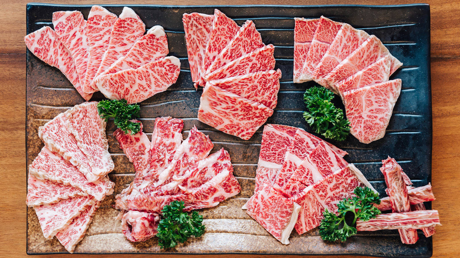 meat 桌布 壁紙 — 雪花和牛肉片在深色石盤上扇形展開，飾以歐芹。