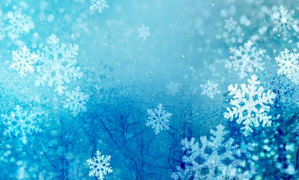 雪花在藍色冬日背景下飄落，樹枝模糊。 — 雪花 GIF 壁紙