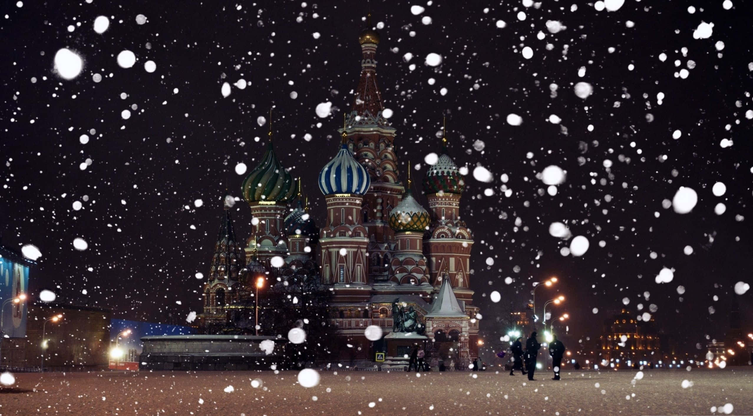 Russia 桌布 壁紙 — 雪花在莫斯科聖瓦西里主教座堂上方的夜空中飄蕩，被溫暖的路燈照亮。