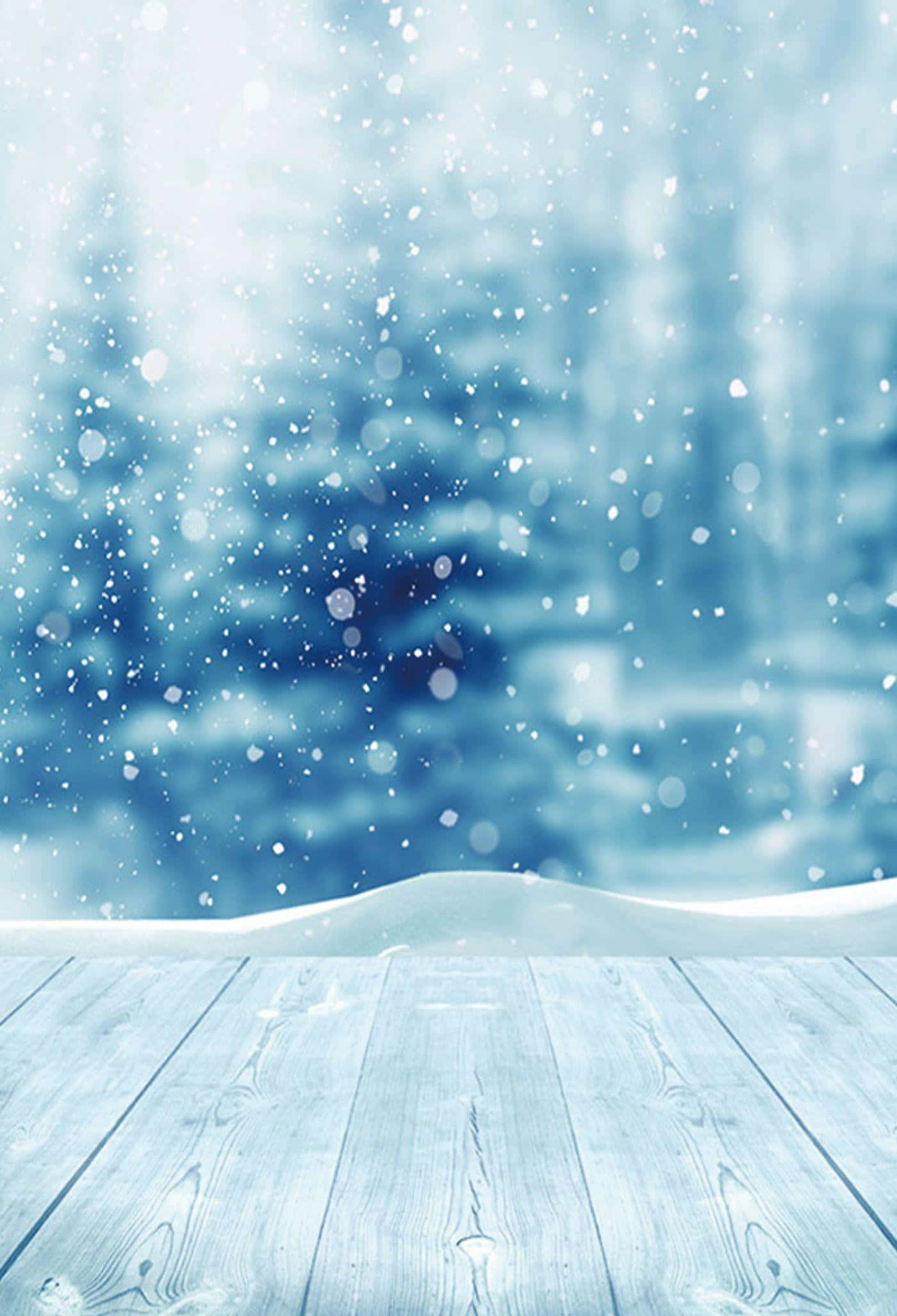 Snow iPhone 桌布 壁紙 — 雪花輕輕飄落在風化的木甲板上，背景是模糊的冬季森林。