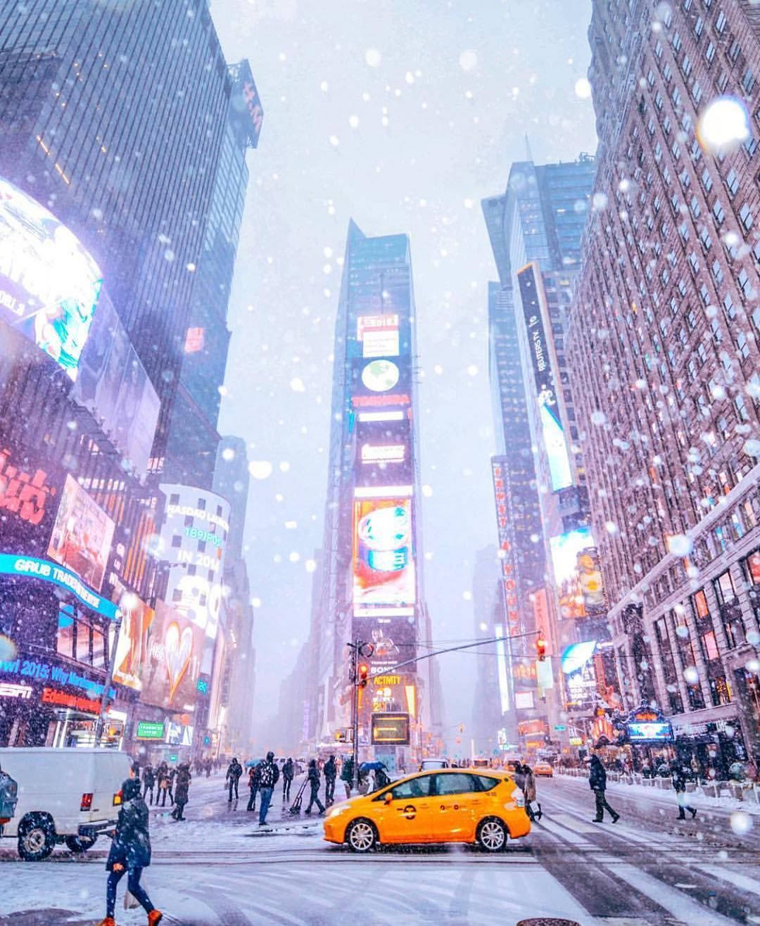 雪 桌布 壁紙 — 雪花飄過時代廣場的霓虹光芒，一輛黃色計程車在摩天大樓廣告牌之間的擁擠街道上行駛。