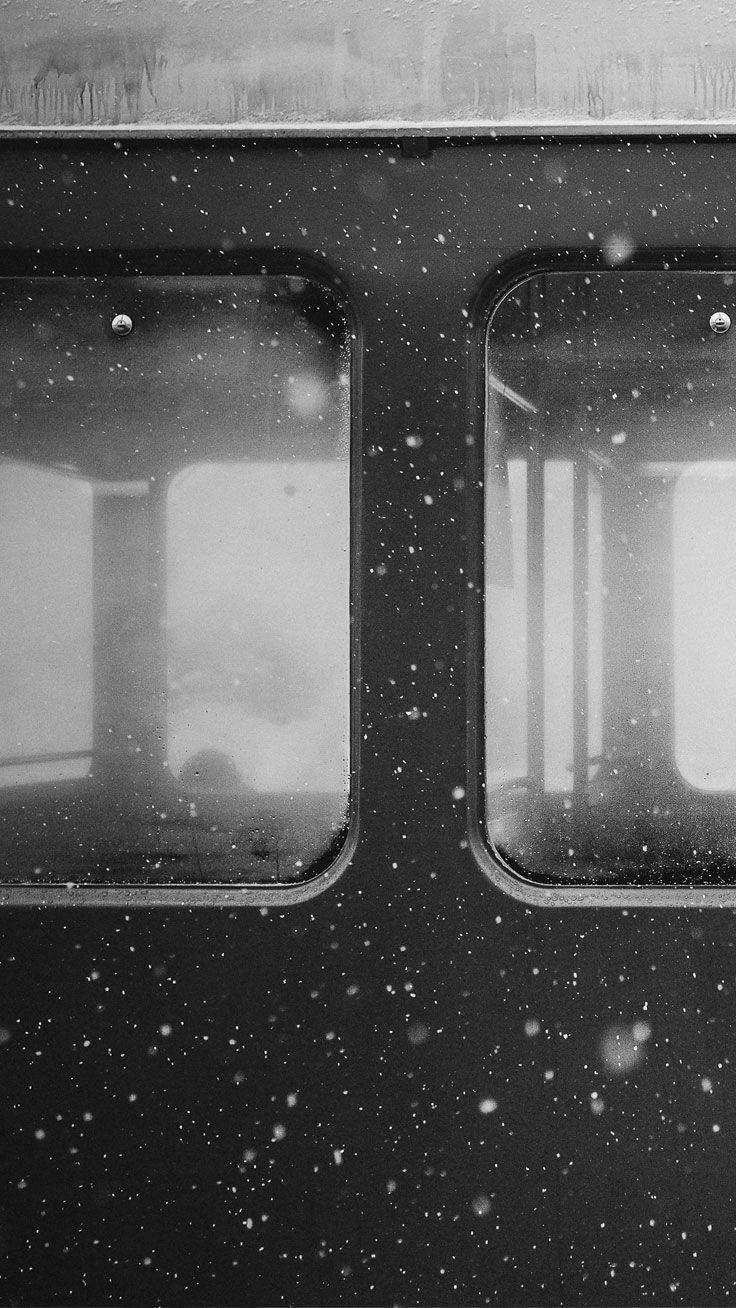 Black And White iPhone 桌布 壁紙 — 雪花飄過火車車廂昏暗的窗戶，以單色顯現模糊的內部陰影。