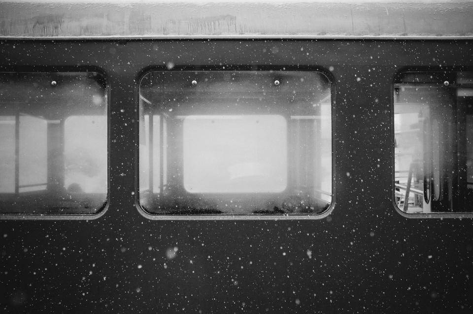 Black And Grey iPhone 桌布 壁紙 — 雪花飄過火車車廂的暗色車窗，顯現出單色調中微弱的內部倒影。