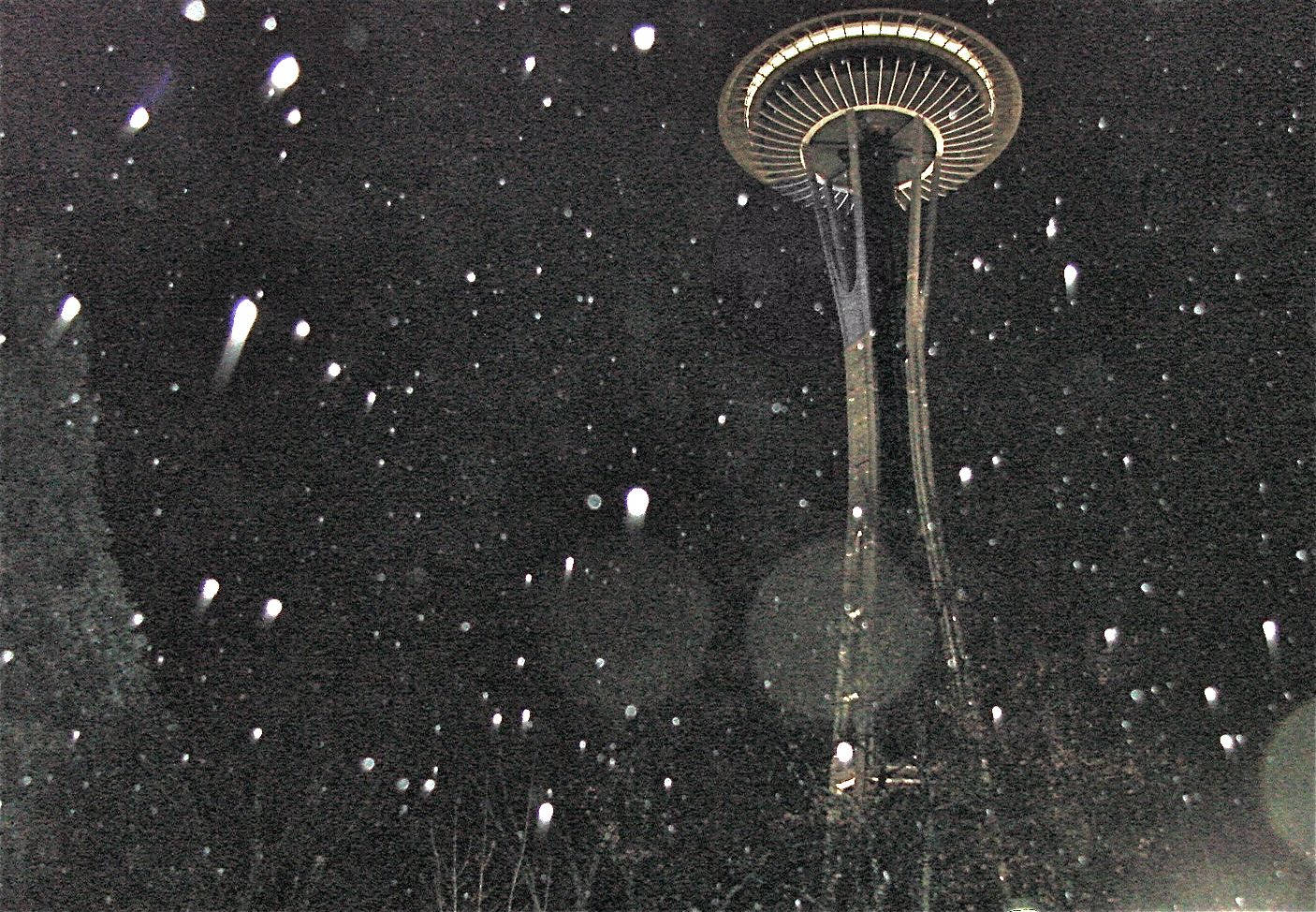 Rainy Day 桌布 壁紙 — 雪花飄過燈火通明的太空針塔，映襯著漆黑的夜空，構成冬日都市景象。