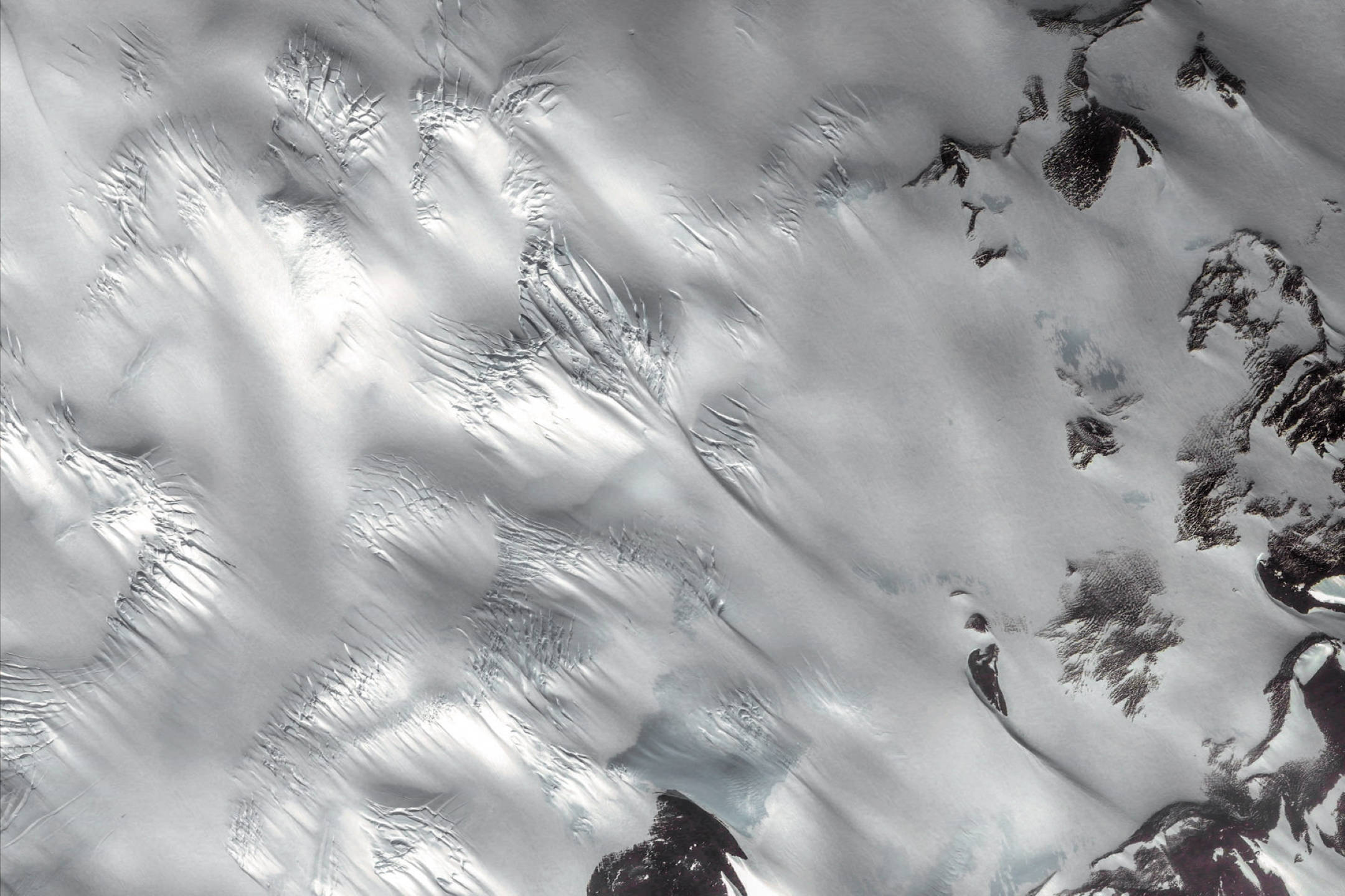 Google 地球 桌布 壁紙 — 雪覆蓋的山脊航拍視圖，具有尖銳的山峰和紋理冰層，在明亮光線下。