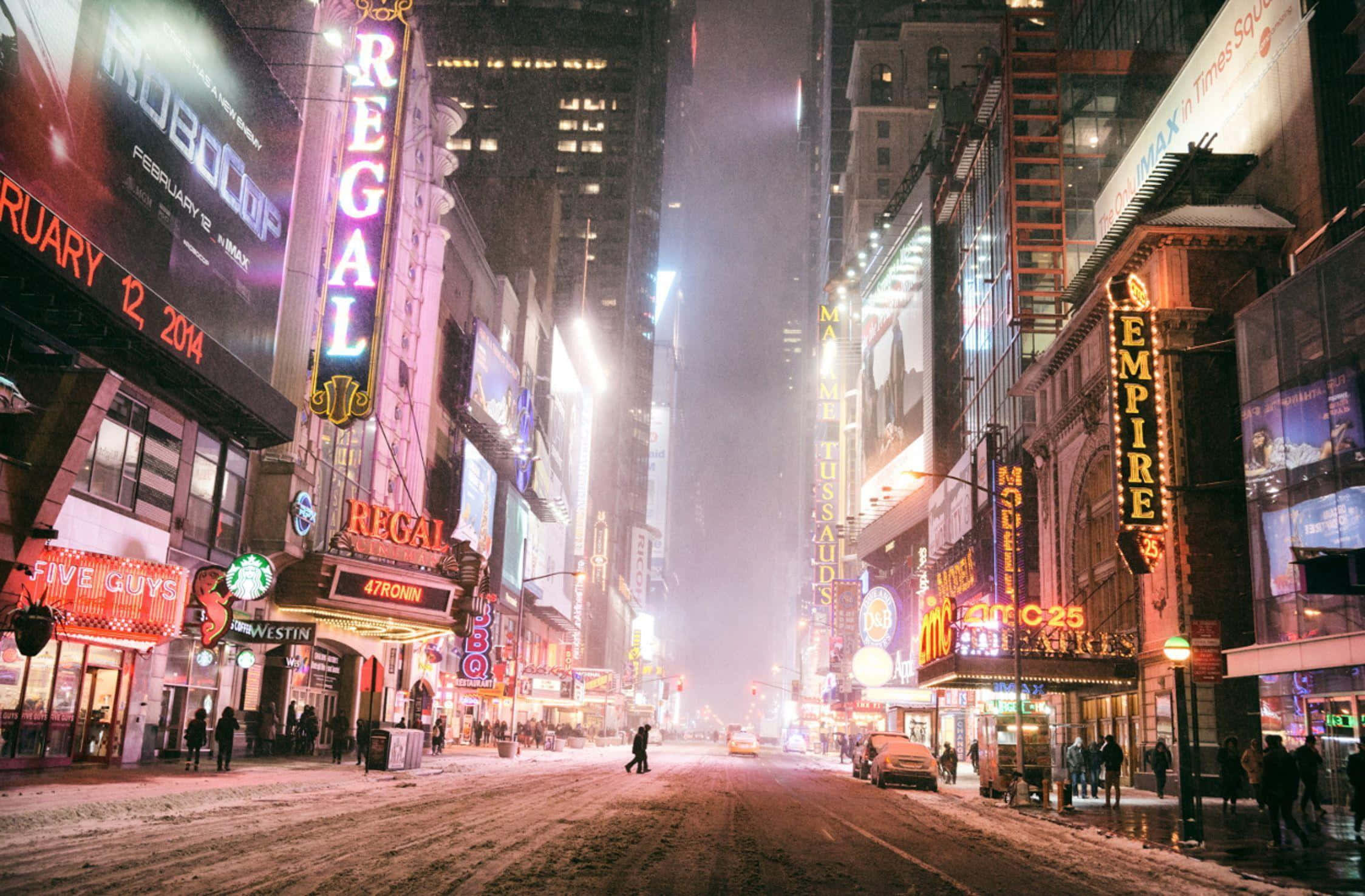 Winter Cityscape 桌布 壁紙 — 雪覆蓋著夜晚霓虹燈照亮的時代廣場，劇院招牌閃爍，行人稀疏。