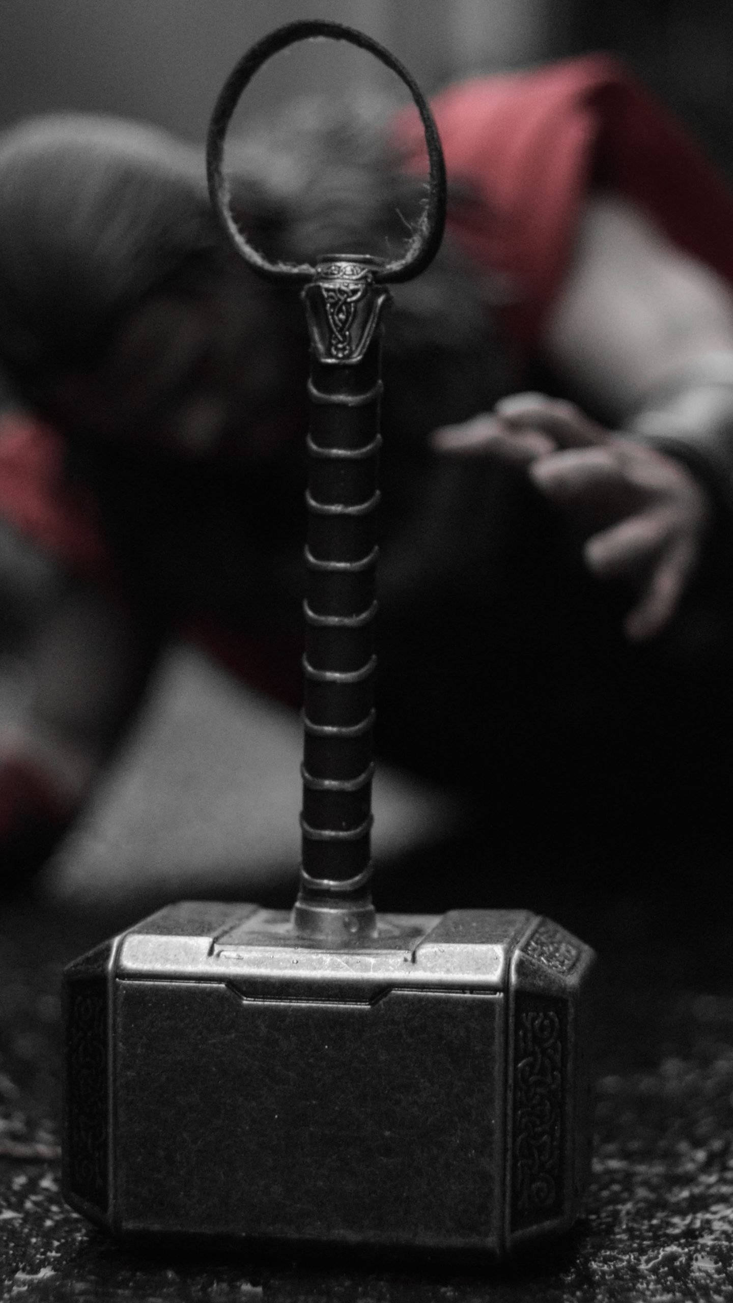 Thor Hammer 桌布 壁紙 — 雷神之鎚妙爾尼爾的特寫，背景有一個模糊的紅灰色身影。
